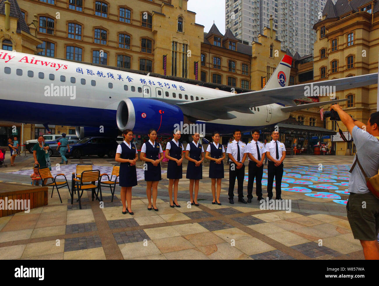 Chinese waitresses and waiters dressed in uniforms of air hostess and pilot pose in front of the Boeing 737-400 airplane restaurant 'Lily Airways' on Stock Photo