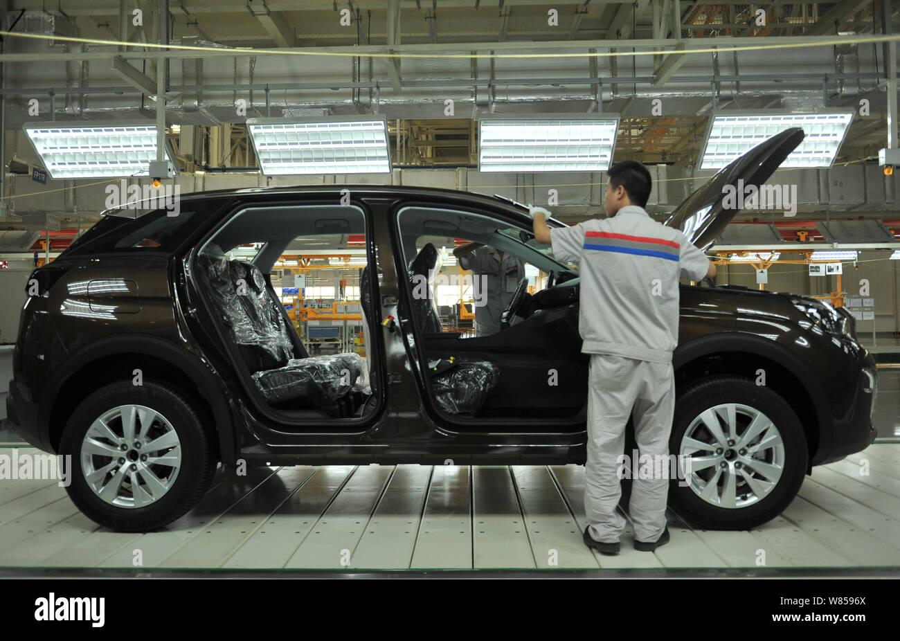 A Chinese factory worker assembles a car on the assembly line at an ...