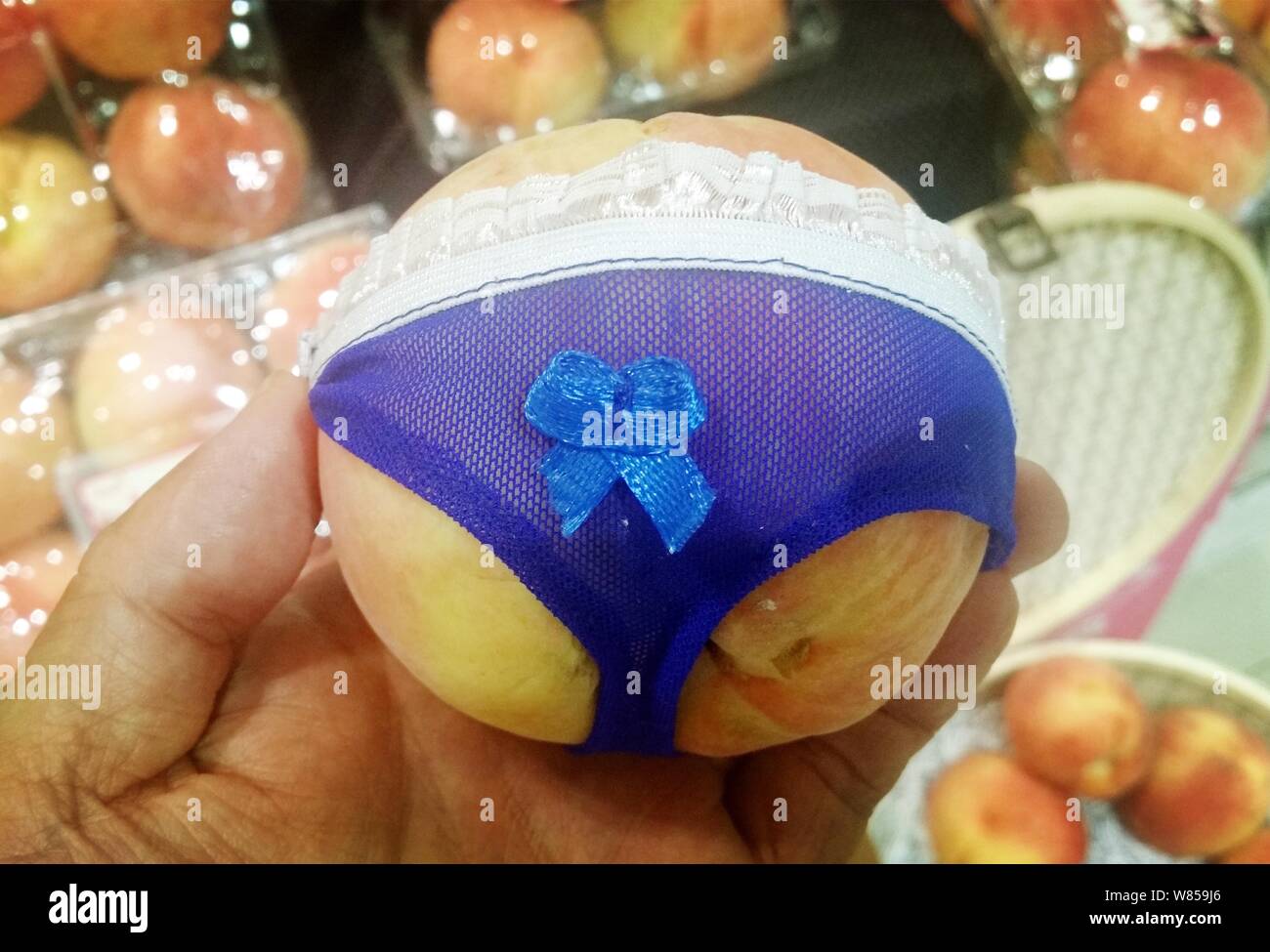A customer shows a panty-wearing peach at a fruit shop in Qingdao