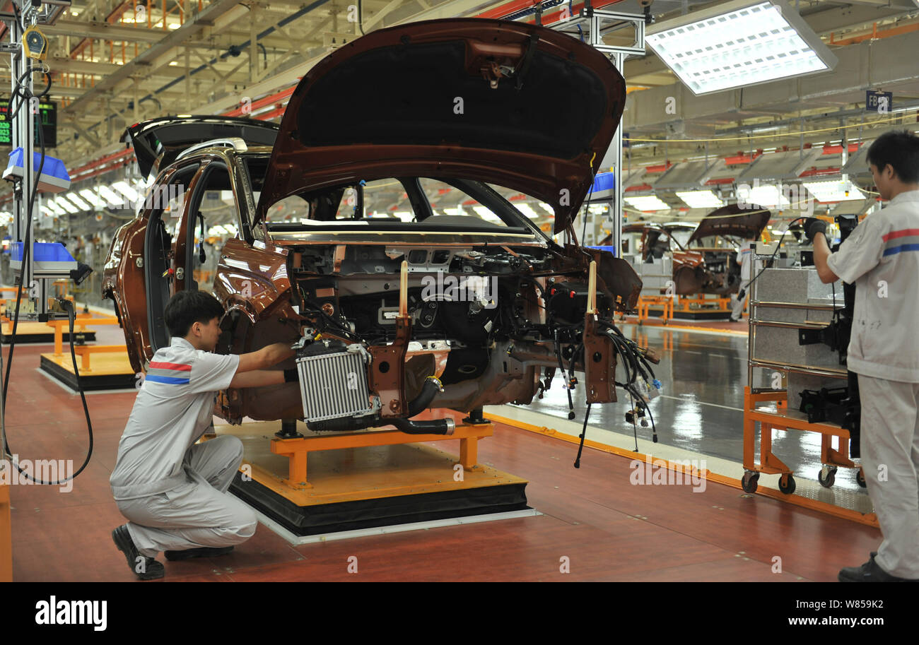 Chinese factory workers assemble cars on the assembly line at an auto ...