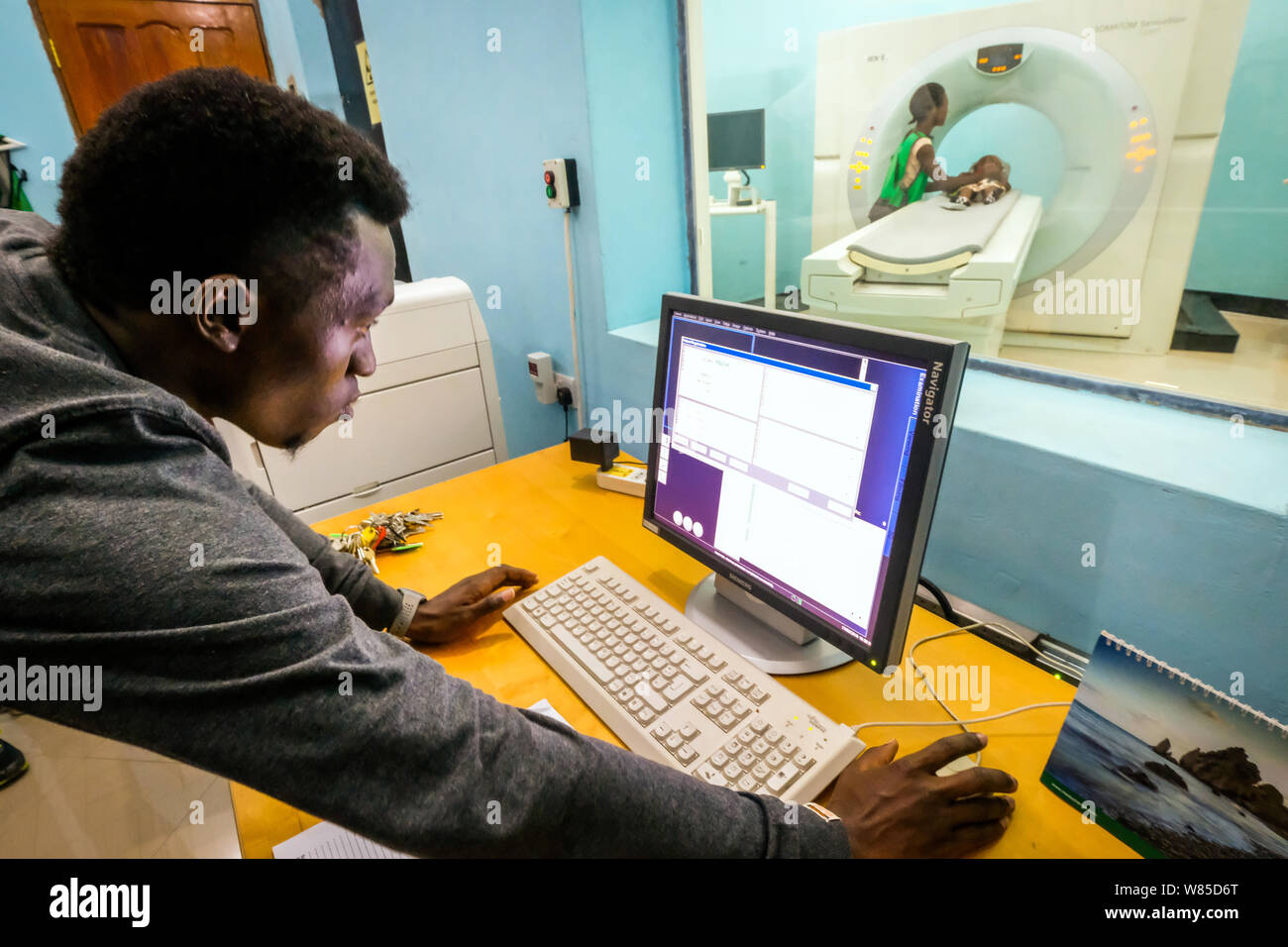 A doctor examines a girl (3 years old) suffering from hydrocephalus (Spina Bifida) in a CT-scanner (computer tomography) at the St. Clare Clinic of the German missionary doctor Dr. med. Thomas Brei in Mwanza, Tanzania, Africa Stock Photo