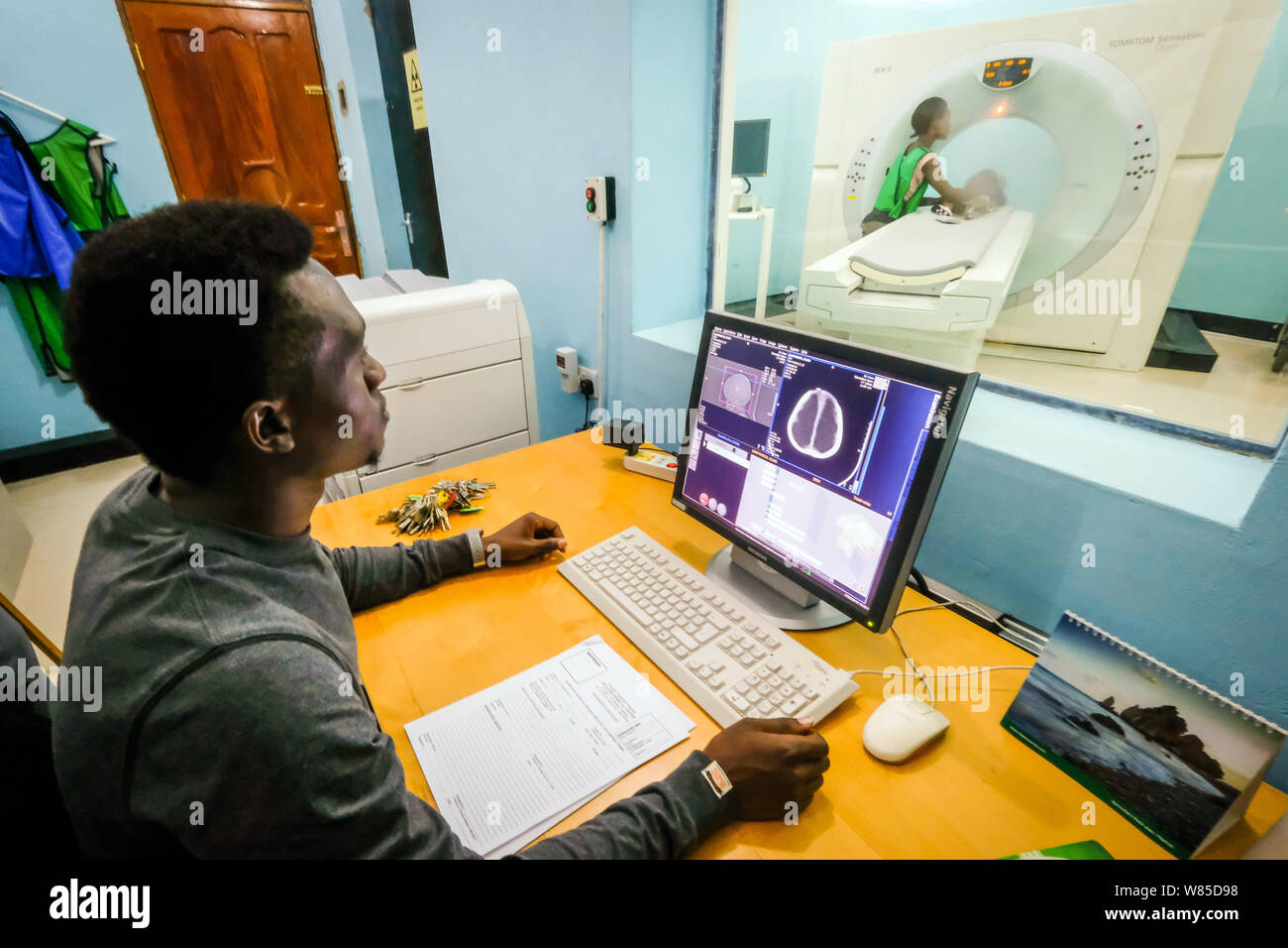 A doctor examines a girl (3 years old) suffering from hydrocephalus (Spina Bifida) in a CT-scanner (computer tomography) at the St. Clare Clinic of the German missionary doctor Dr. med. Thomas Brei in Mwanza, Tanzania, Africa Stock Photo