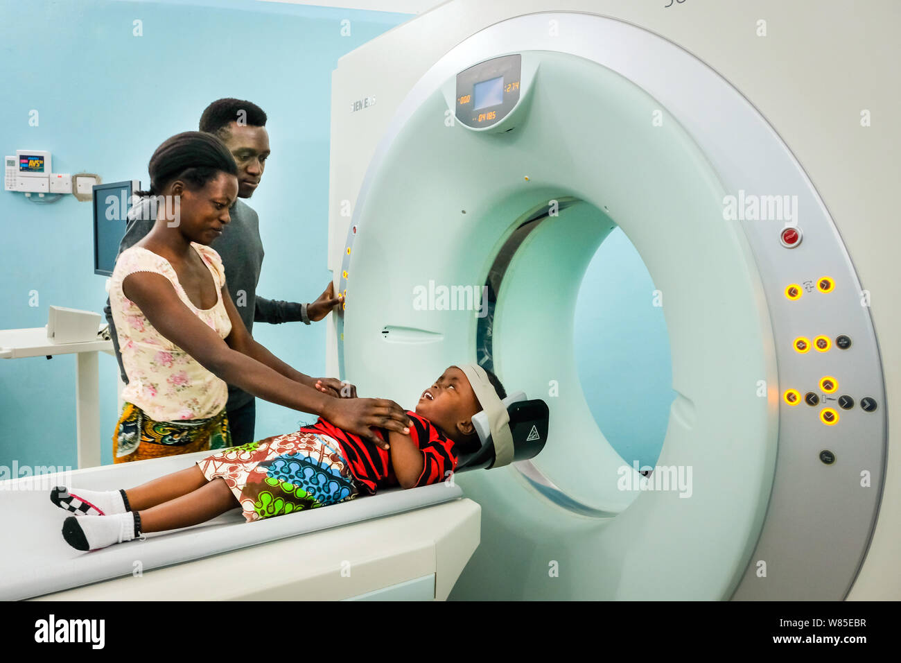 Doctor with m mother and her daughter (3 years old) who is suffering from hydrocephalus (spina bifida) in a CT-scanner (computer tomography) at the catholic St. Clare Clinic of the German missionary doctor Dr. med. Thomas Brei in Mwanza, Tanzania, Africa Stock Photo