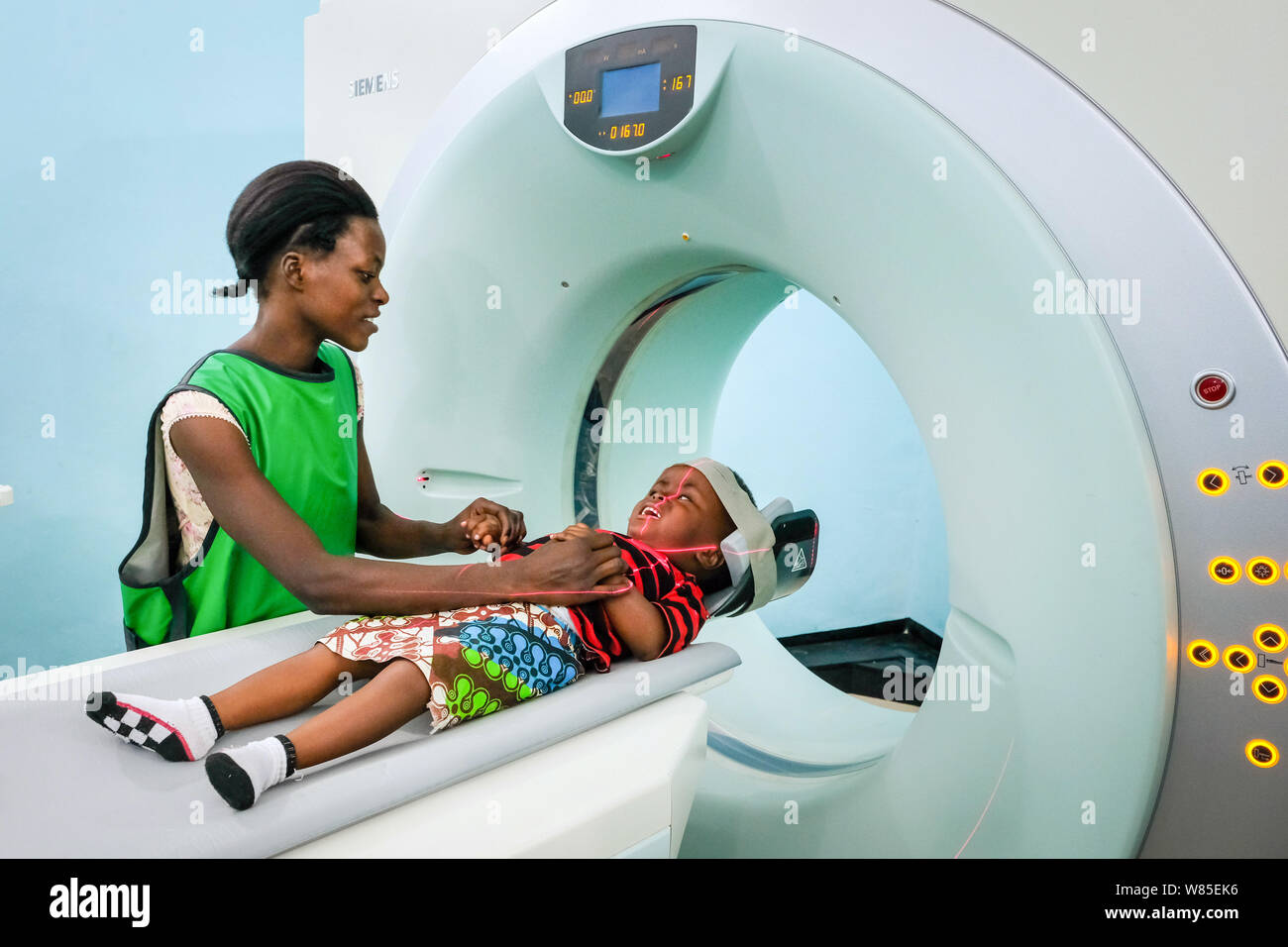 A mother and her daughter (3 years old) who is suffering from hydrocephalus (spina bifida) in a CT-scanner (computer tomography) at the catholic St. Clare Clinic of the German missionary doctor Dr. med. Thomas Brei in Mwanza, Tanzania, Africa Stock Photo