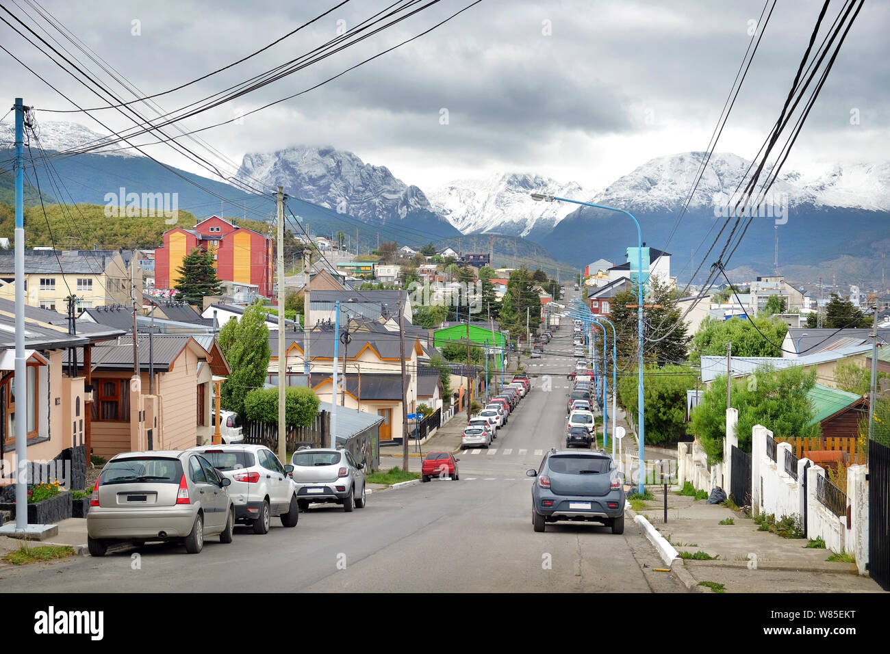 Cars on the streets of Ushuaia, in Tierra del Fuego, Argentina, surrounded by green vegetation, during a clouded day with a grey sky. Stock Photo