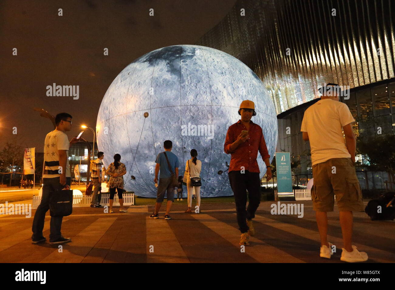 Visitors look at a giant sphere simulating the moon to celebrate the ...
