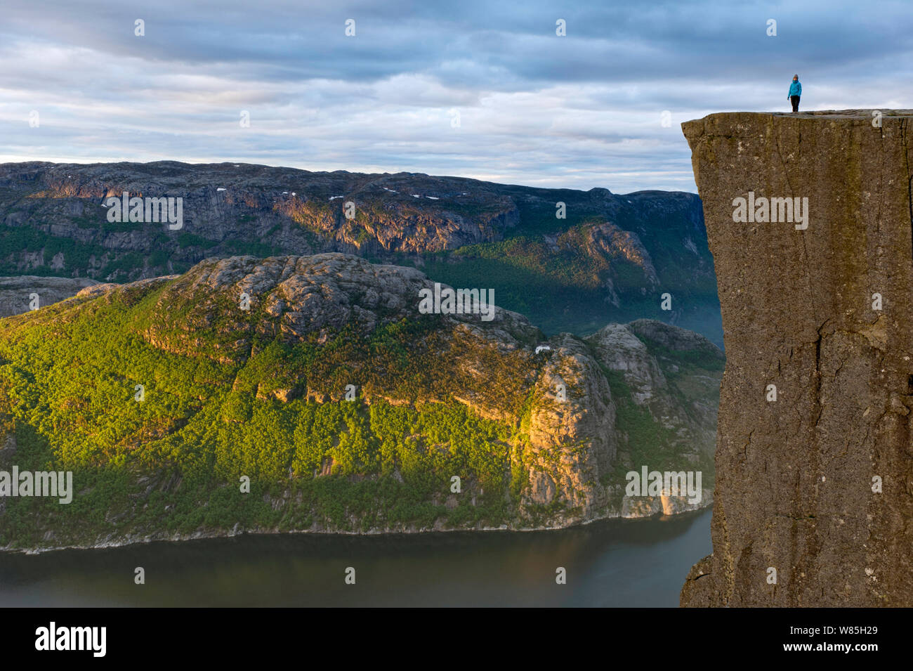 Person standing on The Preikestolen (Pulpit rock) at the Lysefjorden. Forsand, Rogaland, Norway, June 2012. Stock Photo