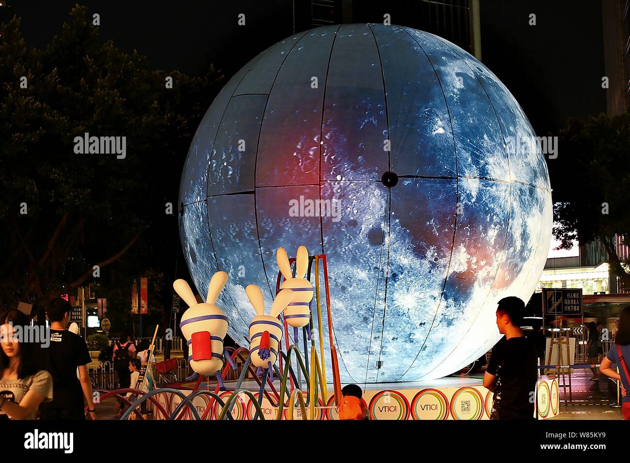 --FILE--Pedestrians walk past a giant sphere simulating the moon to ...