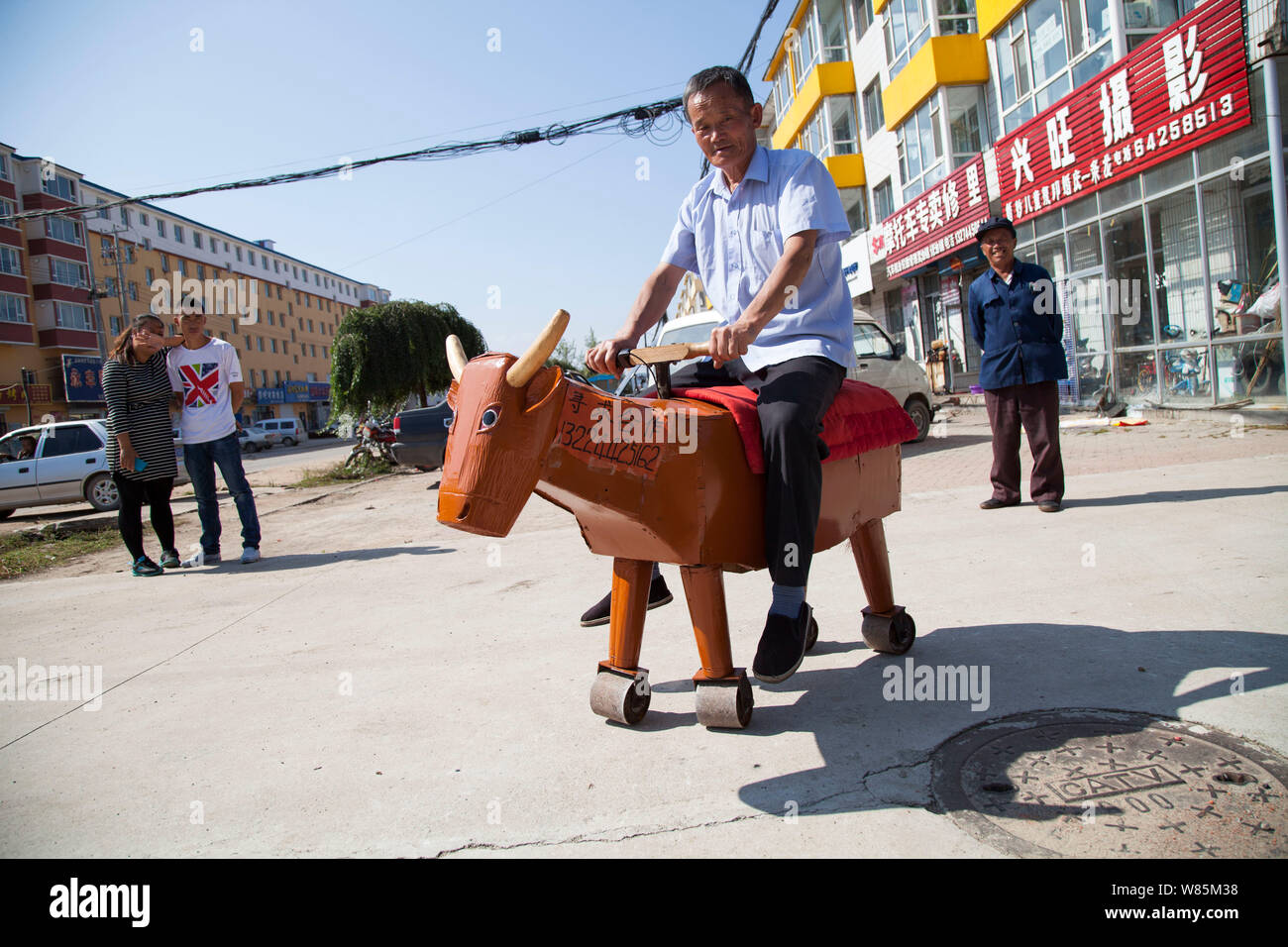 Chinese carpenter Li Jingyang rides a homemade wooden ox on a road in