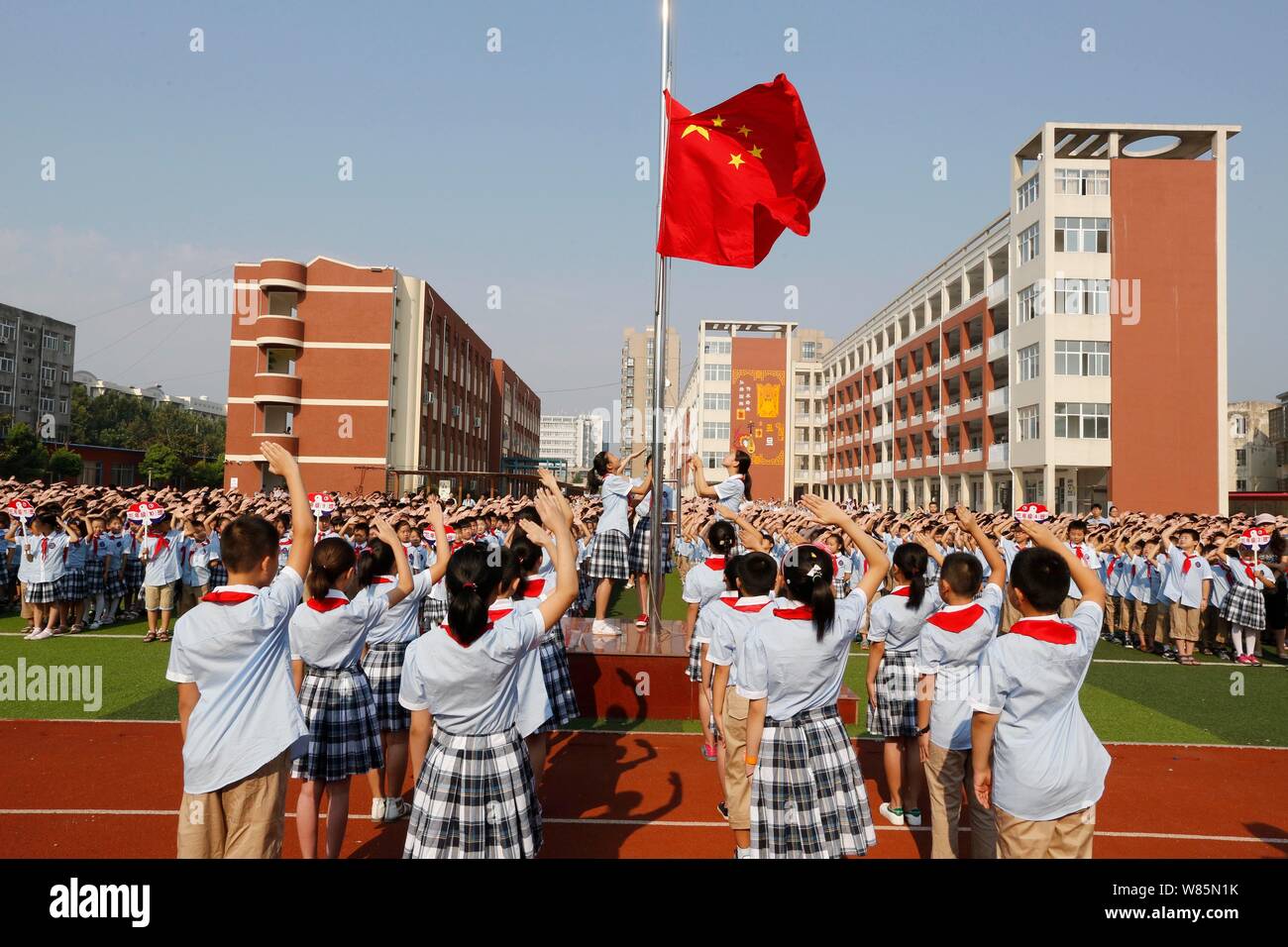 Young Chinese students salute during a flagraising ceremony at a primary school on the first