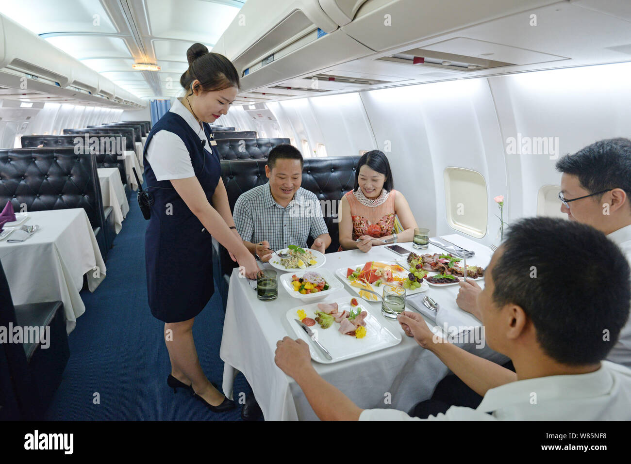 A Chinese waitress dressed in a uniform of air hostess serves for customers on the Boeing 737-400 airplane restaurant 'Lily Airways' on the Optics Val Stock Photo