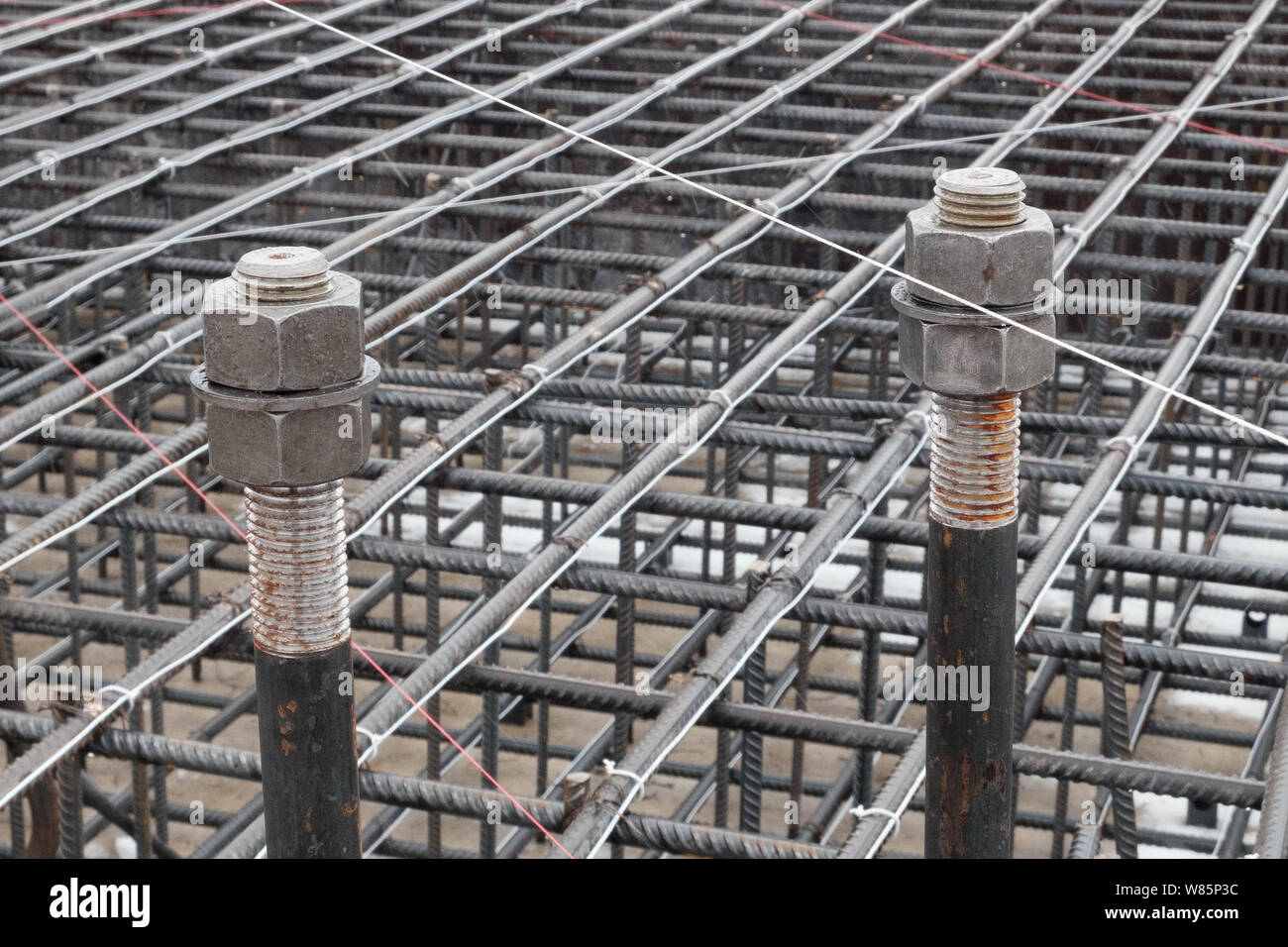 Two steel anchor bolts with screw nuts and steel grid on tower crane
