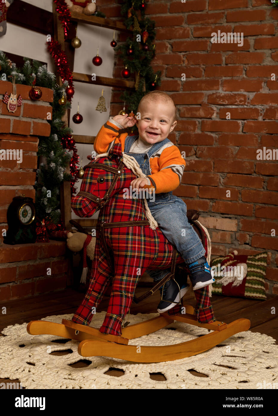 Little baby boy on rocking horse, dressed in sweater and jeans