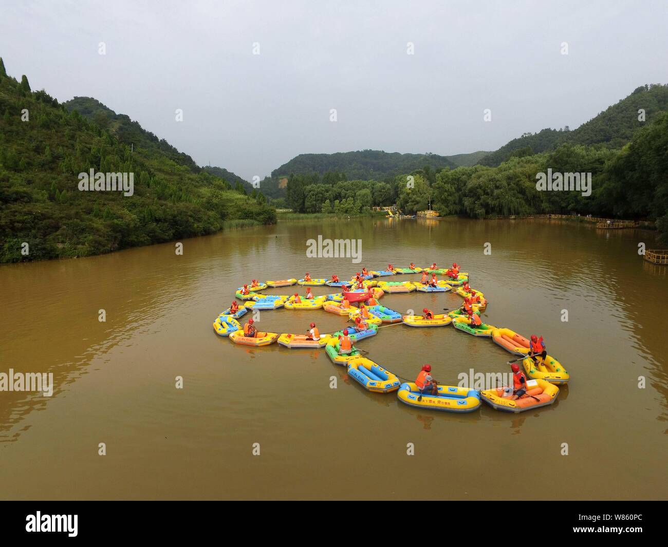 Local residents row inflatable rafts to form the Olympic rings to cheer ...