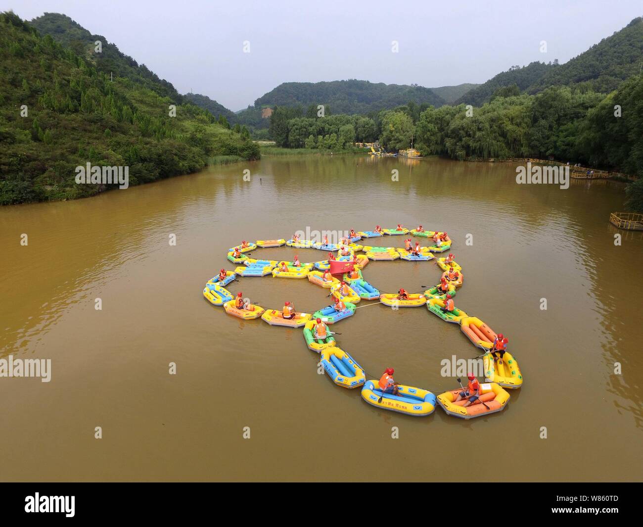 Local residents row inflatable rafts to form the Olympic rings to cheer ...