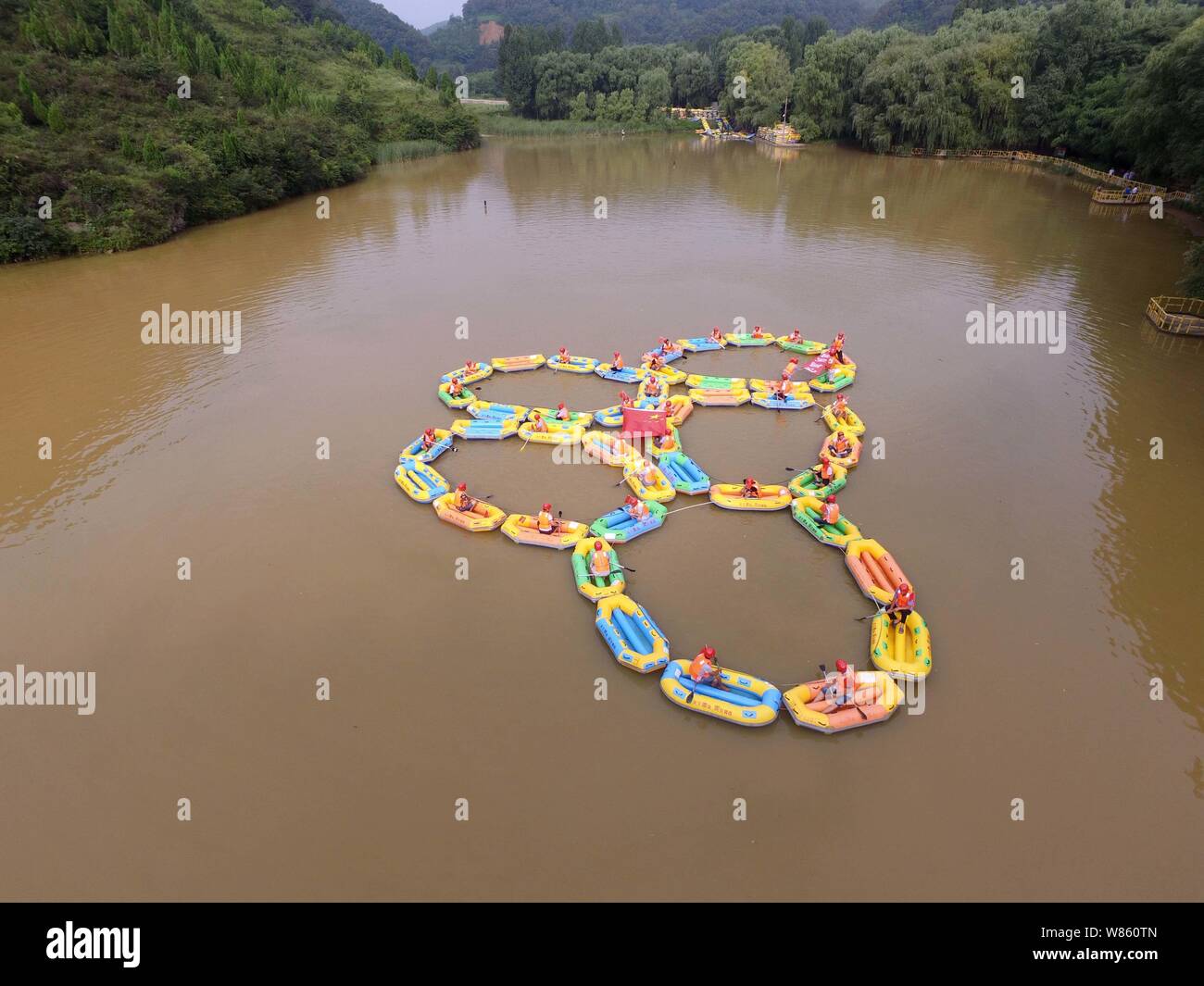 Local residents row inflatable rafts to form the Olympic rings to cheer ...