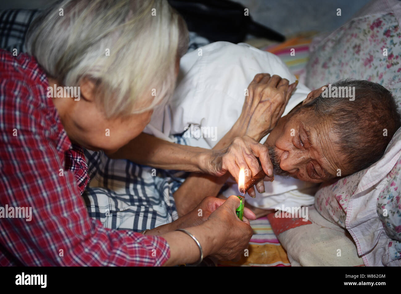 103-year-old Lin Yongqing who was a bank cashier smokes on the bed at home in Chengdu city, southwest China's Sichuan province, 1 August 2016.   A 103 Stock Photo