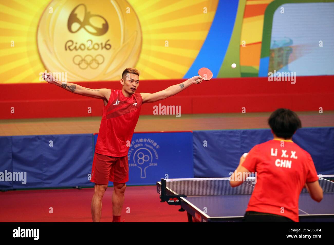 Chinese badminton star Lin Dan, back, competes with table tennis player Li Xiaoxia at a table tennis demonstration event during the visit of Rio Olymp Stock Photo