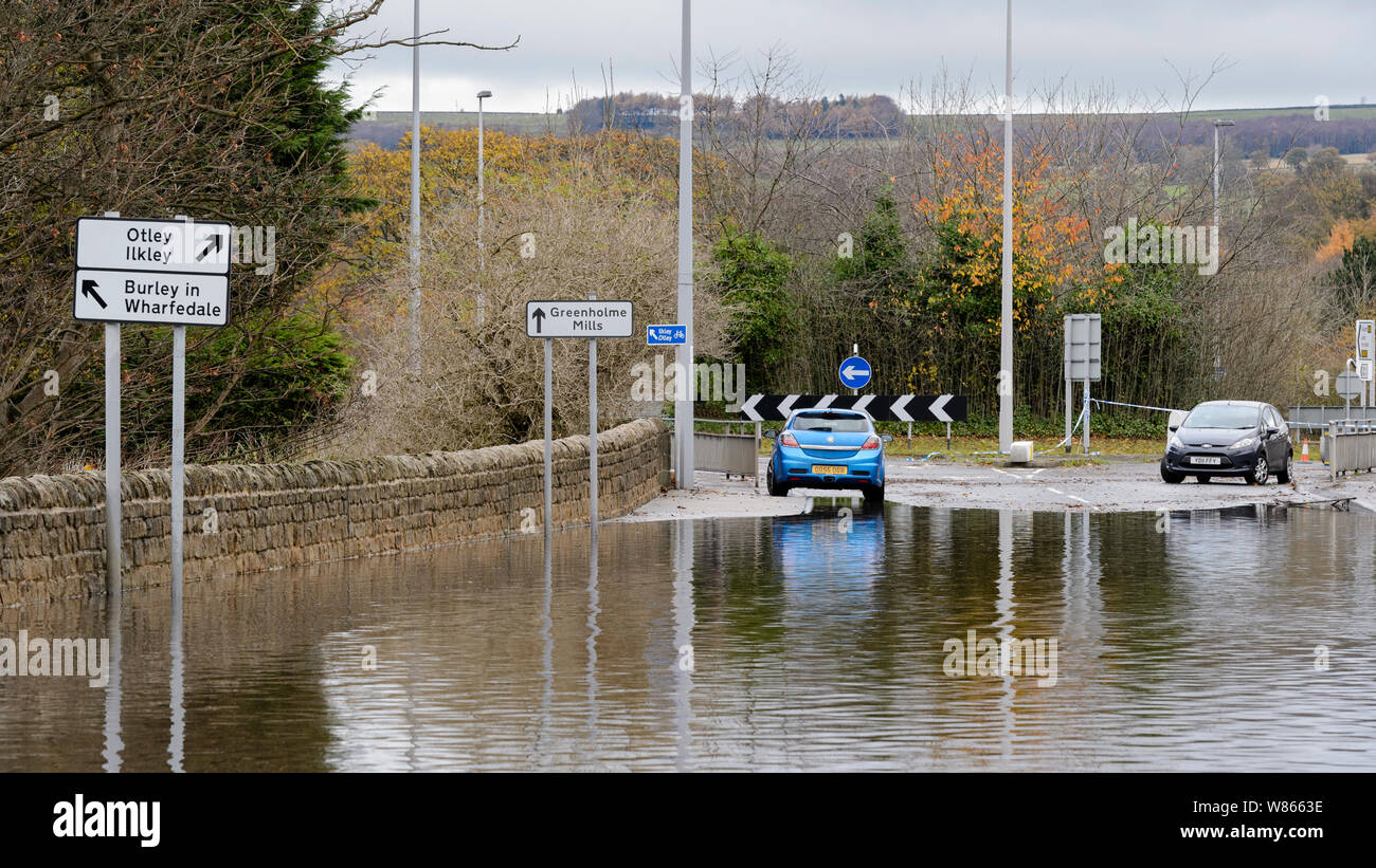 Flooding - flooded road is impassable to cars as deep flood water makes driving hazardous for vehicles - Burley In Wharfedale, Yorkshire, England, UK. Stock Photo