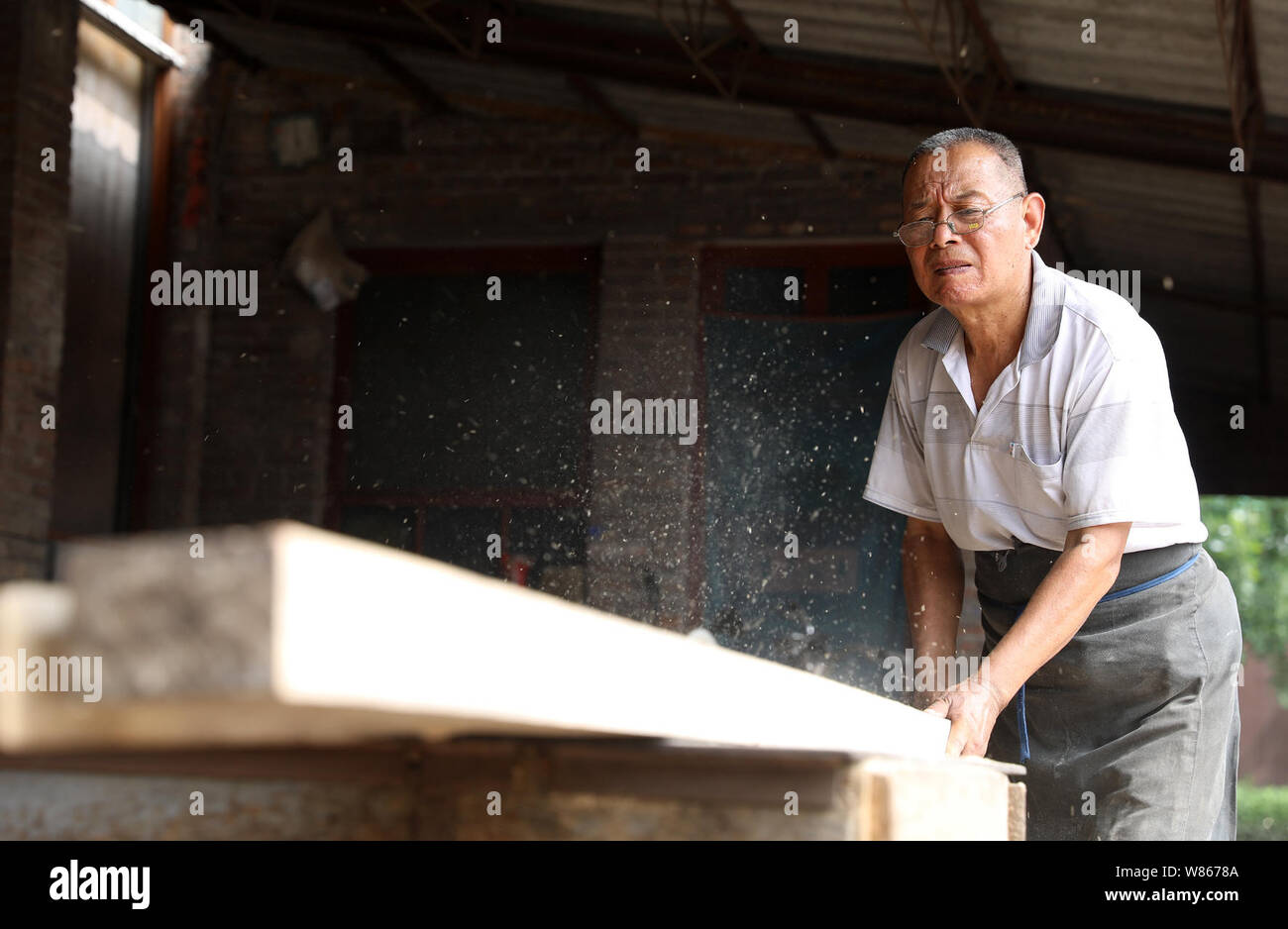 (190808) -- SHIJIAZHUANG, Aug. 8, 2019 (Xinhua) -- Han Baoyuan cuts a piece of wood in Hengxi Village of Jingxing mining area in Shijiazhuang, capital of north China's Hebei Province, Aug. 7, 2019. Han Baoyuan, a 70-year-old craftsman, is an inheritor of Jingxing traditional skill of building and repairing wood components of architectures. Han has been devoting himself to the career since he was 13, and completed numerous works featuring elegant ancient style. The skill passed down from the Qing Dynasty (1644-1911) has been listed in the seventh batch of municipal-level intangible cultural her Stock Photo