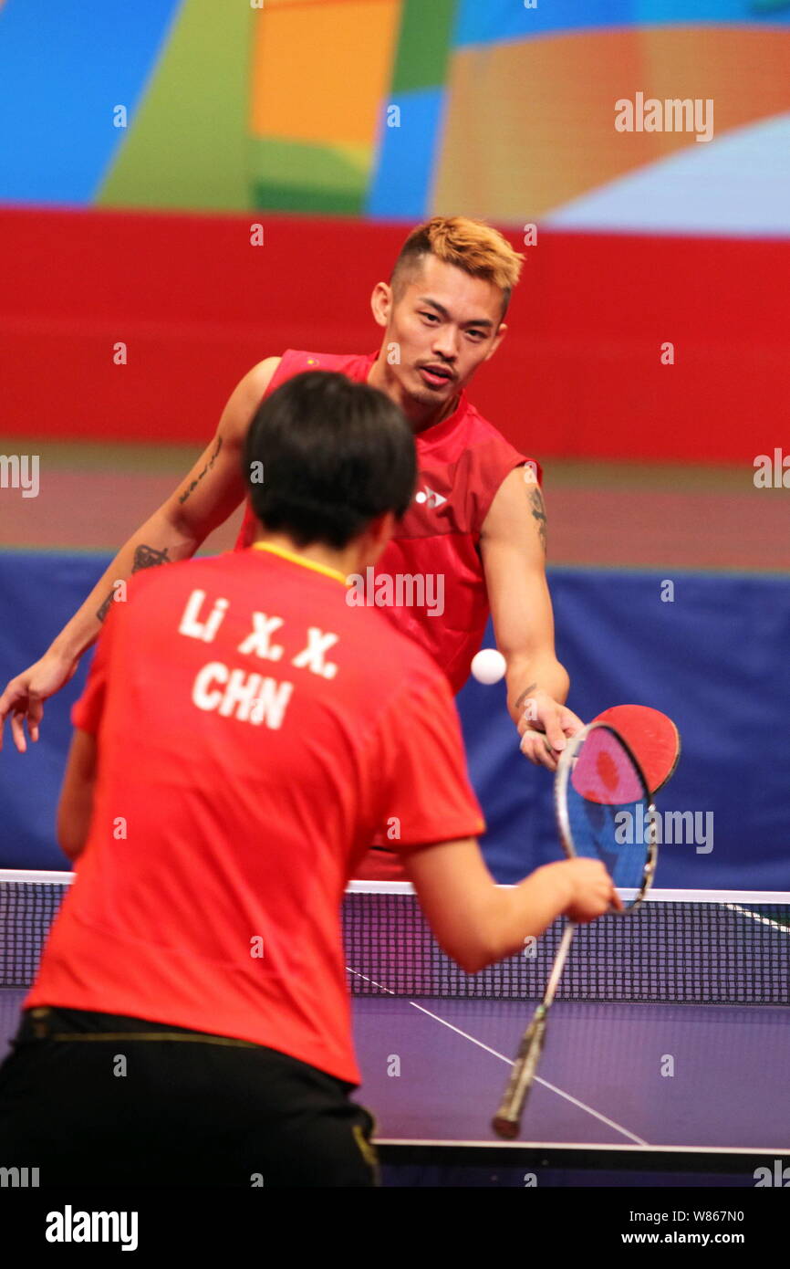 Chinese badminton star Lin Dan, back, competes with table tennis player Li Xiaoxia at a table tennis demonstration event during the visit of Rio Olymp Stock Photo