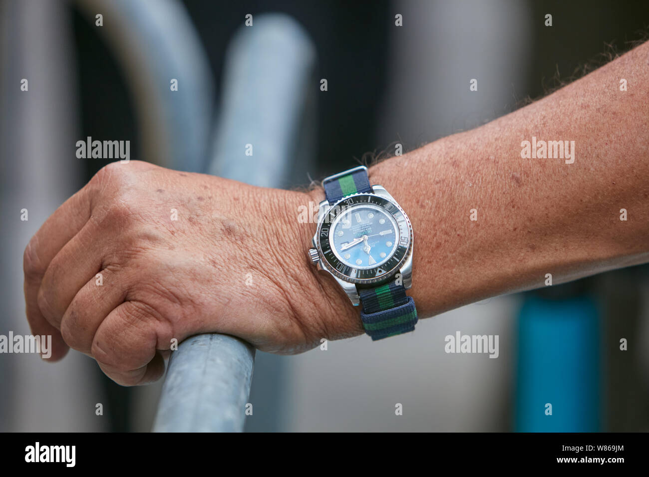 MILAN, ITALY - JUNE 15, 2019: Man with Rolex Deepsea Sea Dweller watch with striped fabric strap before Emporio Armani fashion show, Milan Fashion Wee Stock Photo