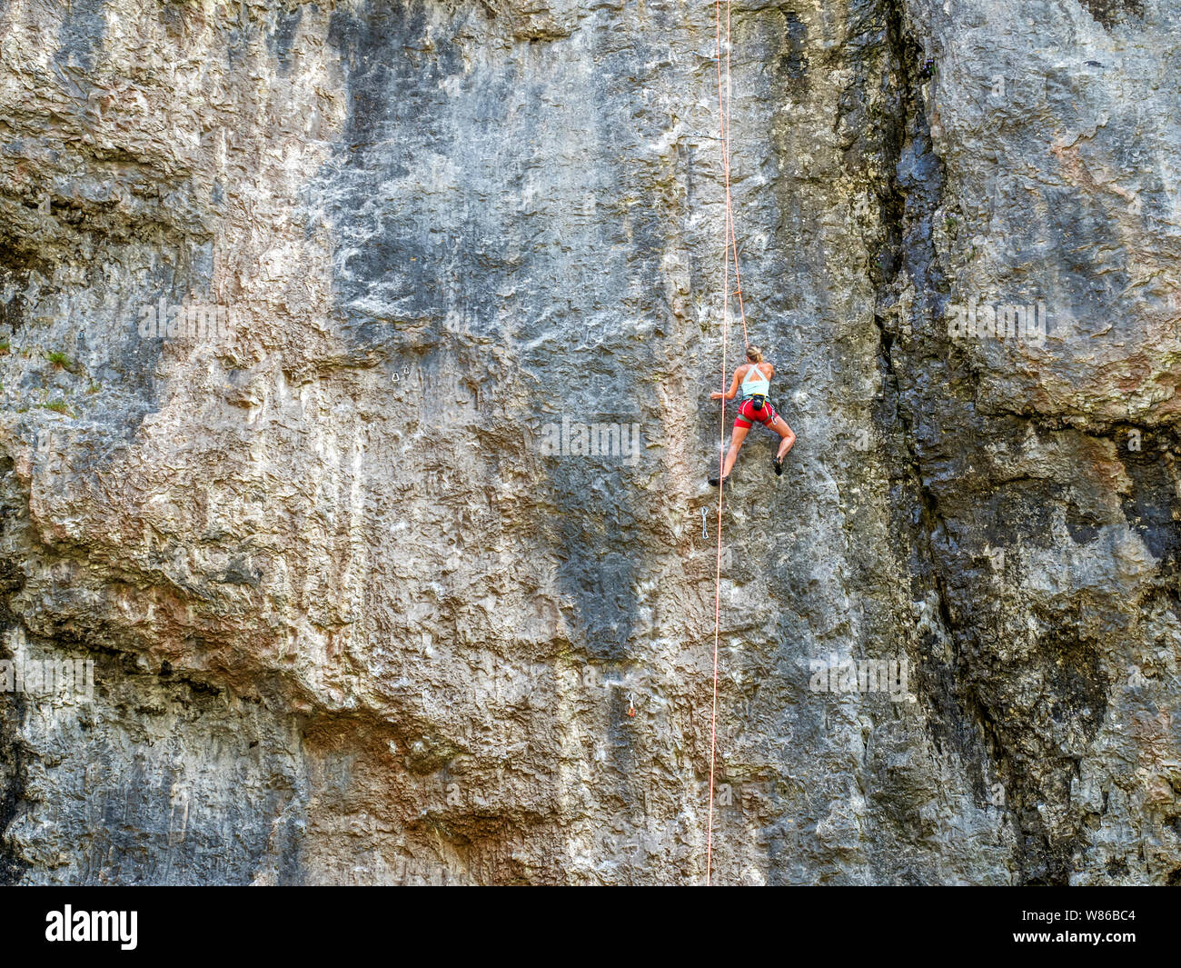 Female rock climber on a limestone cliff at Gordale Scar near Malham Yorkshire Dales National Park England Stock Photo