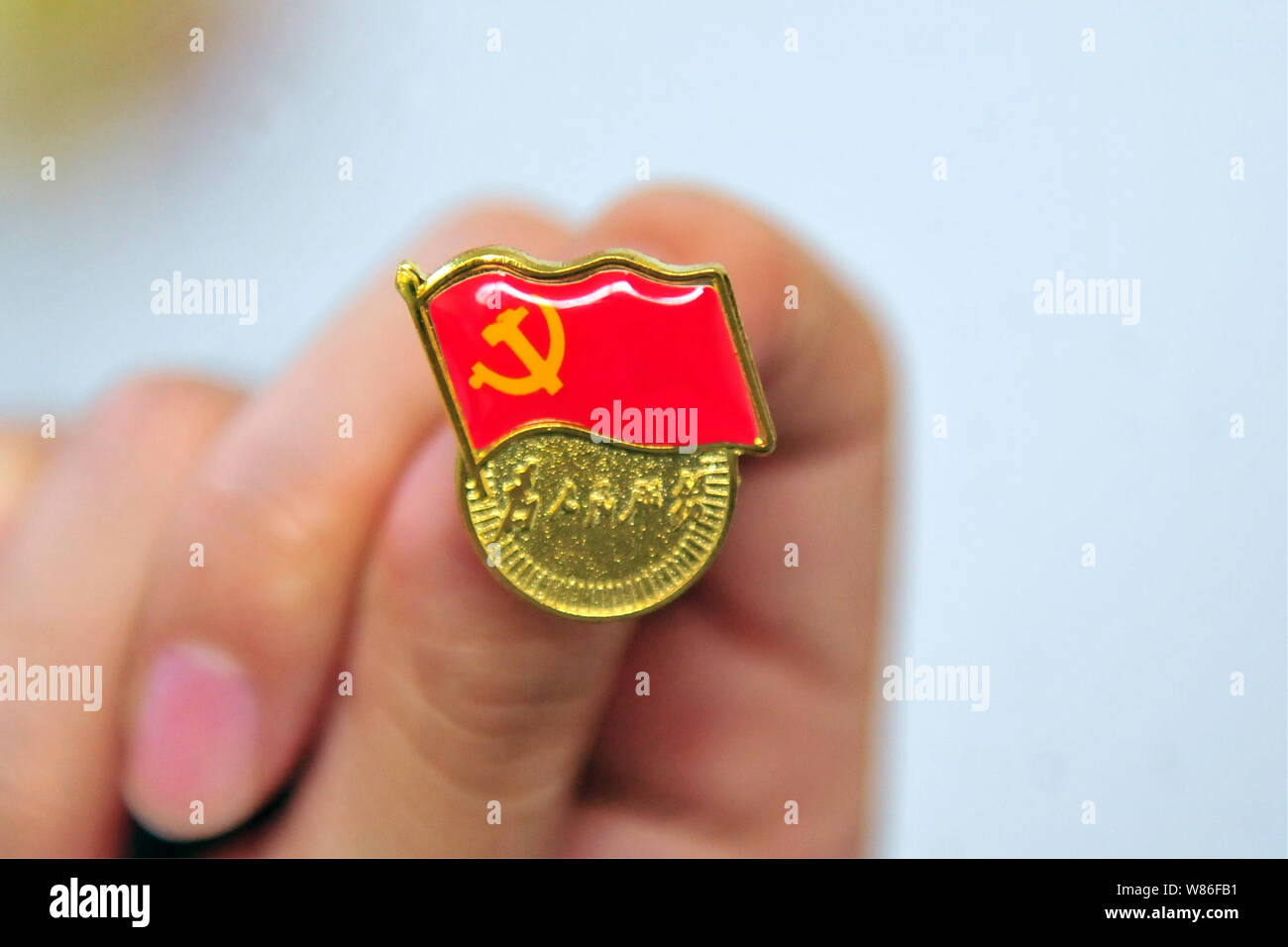 A Chinese member of the Communist Party of China shows a party badge during a contest to celebrate the 95th anniversary of the founding of the CPC in Stock Photo