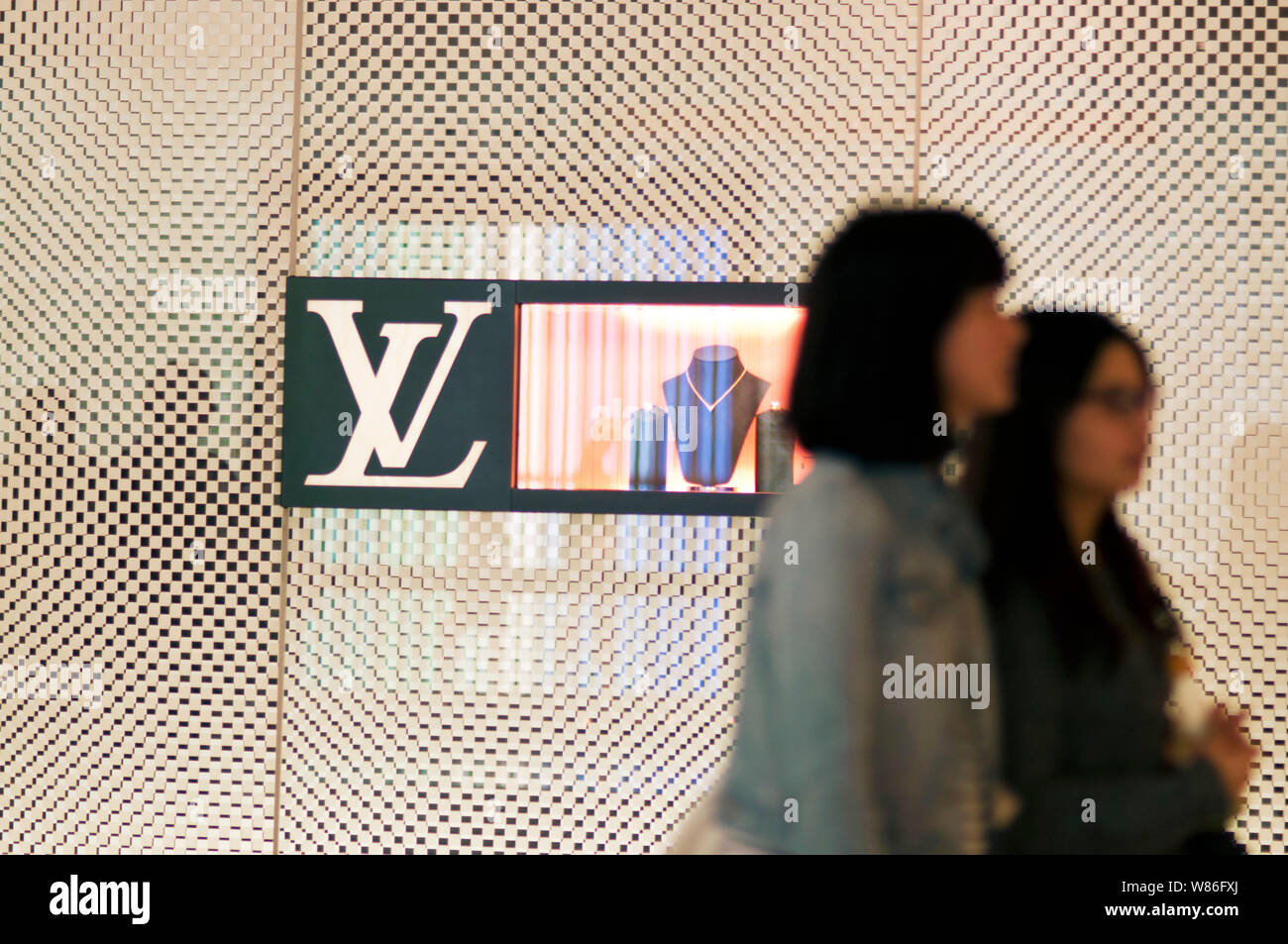 Customers walk past a Louis Vuitton (LV) store at a shopping mall