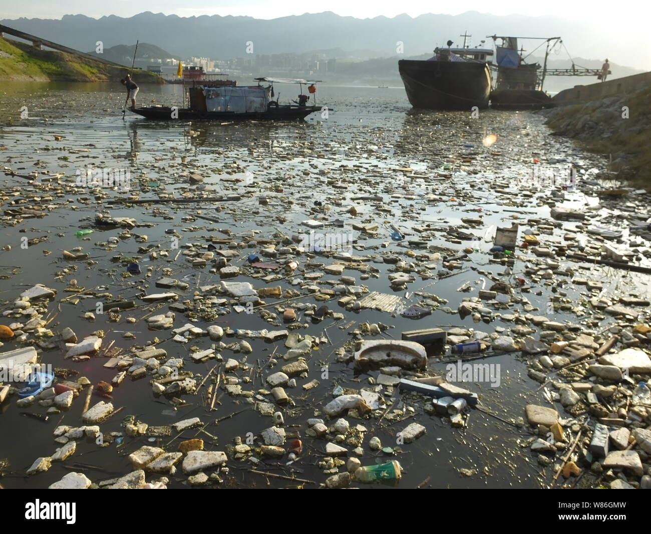 A Chinese worker collects garbage floating on the Yangtze River in the ...