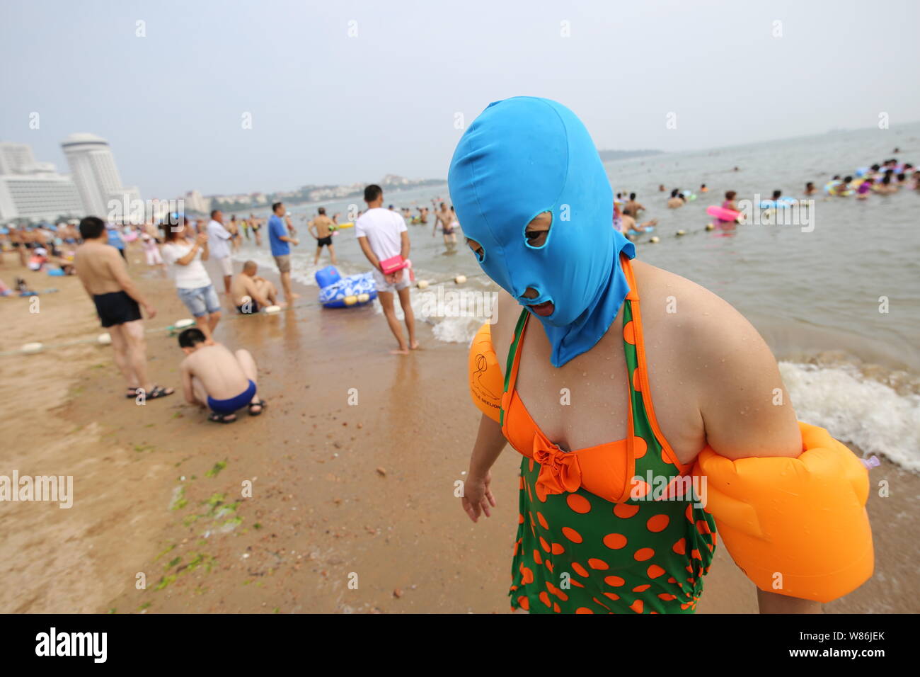 A Chinese woman wearing a facekini walks at a beach resort in Qingdao city,  east China's Shandong province, 5 July 2016. Summer is here! With temper  Stock Photo - Alamy