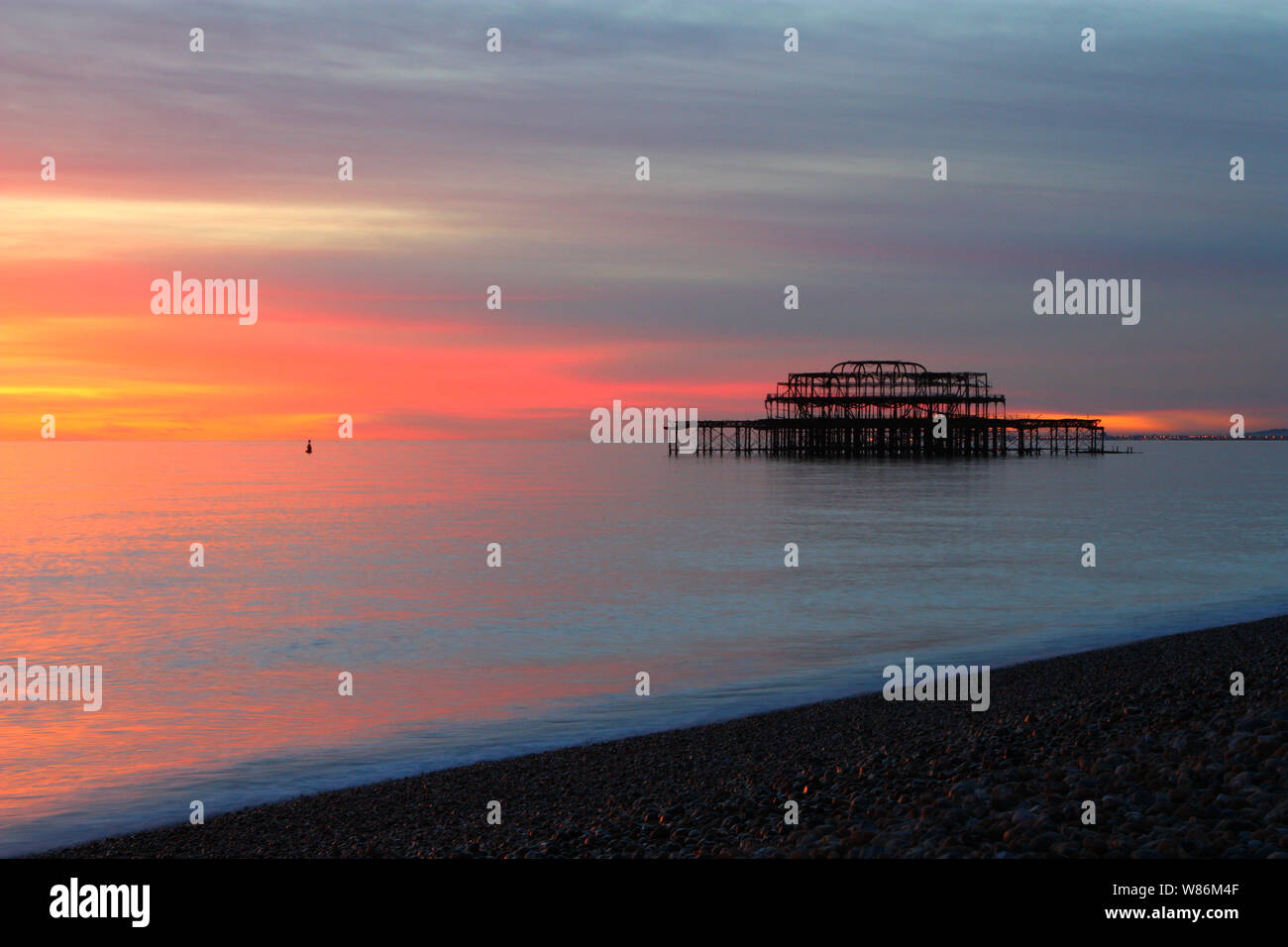 Slow exposure at sunset of the West Pier taken from Brighton Beach, East Sussex, England showing motion blur of waves Stock Photo