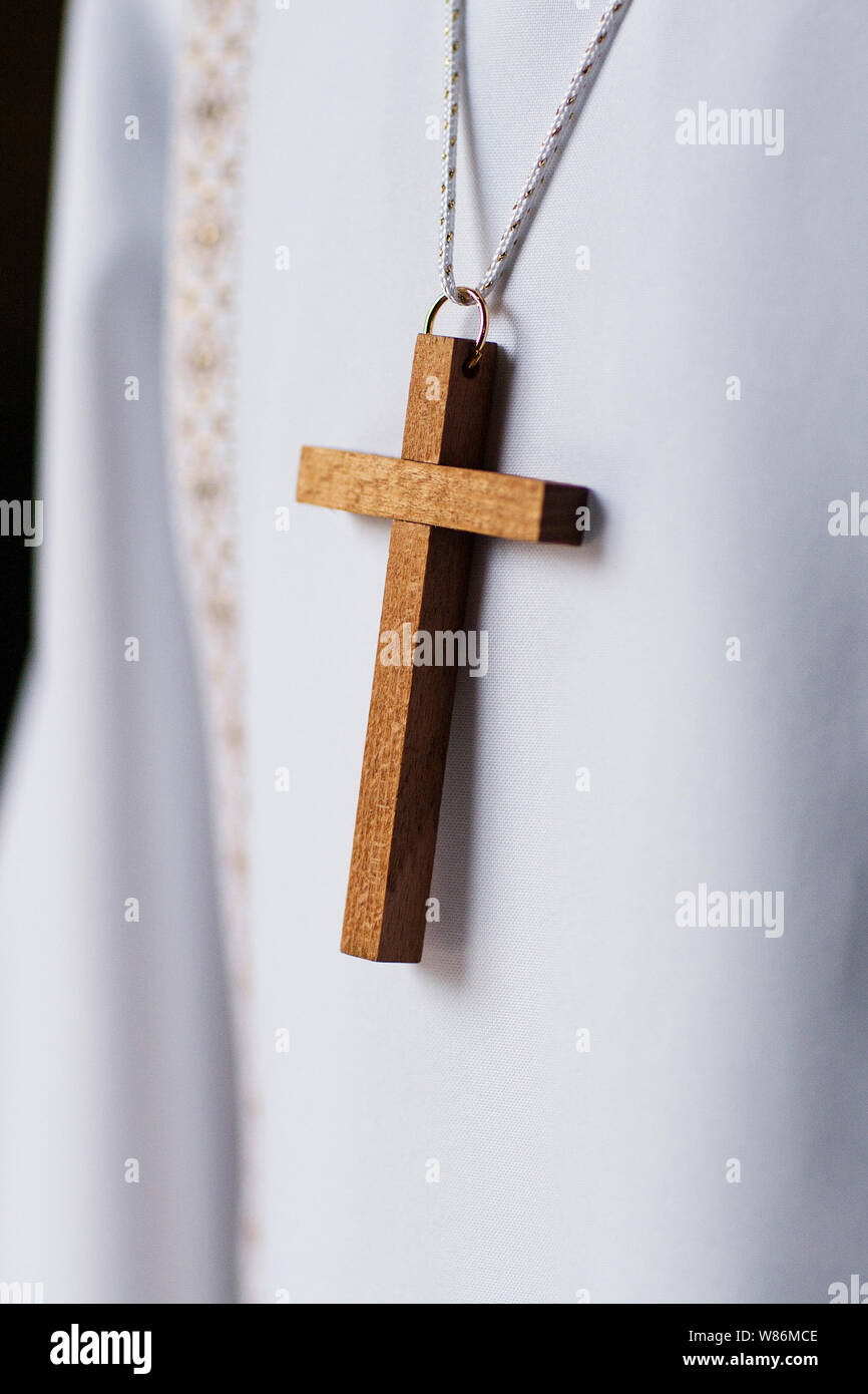 clos up of a crucifix placed on a child's white communion tunic Stock Photo