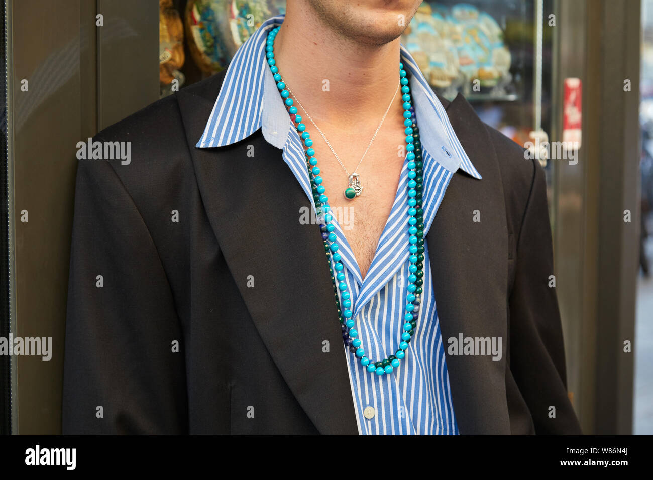 MILAN, ITALY - JUNE 16, 2019: Man with blue and white striped shirt and turquoise necklace before Palm Angels fashion show, Milan Fashion Week street Stock Photo