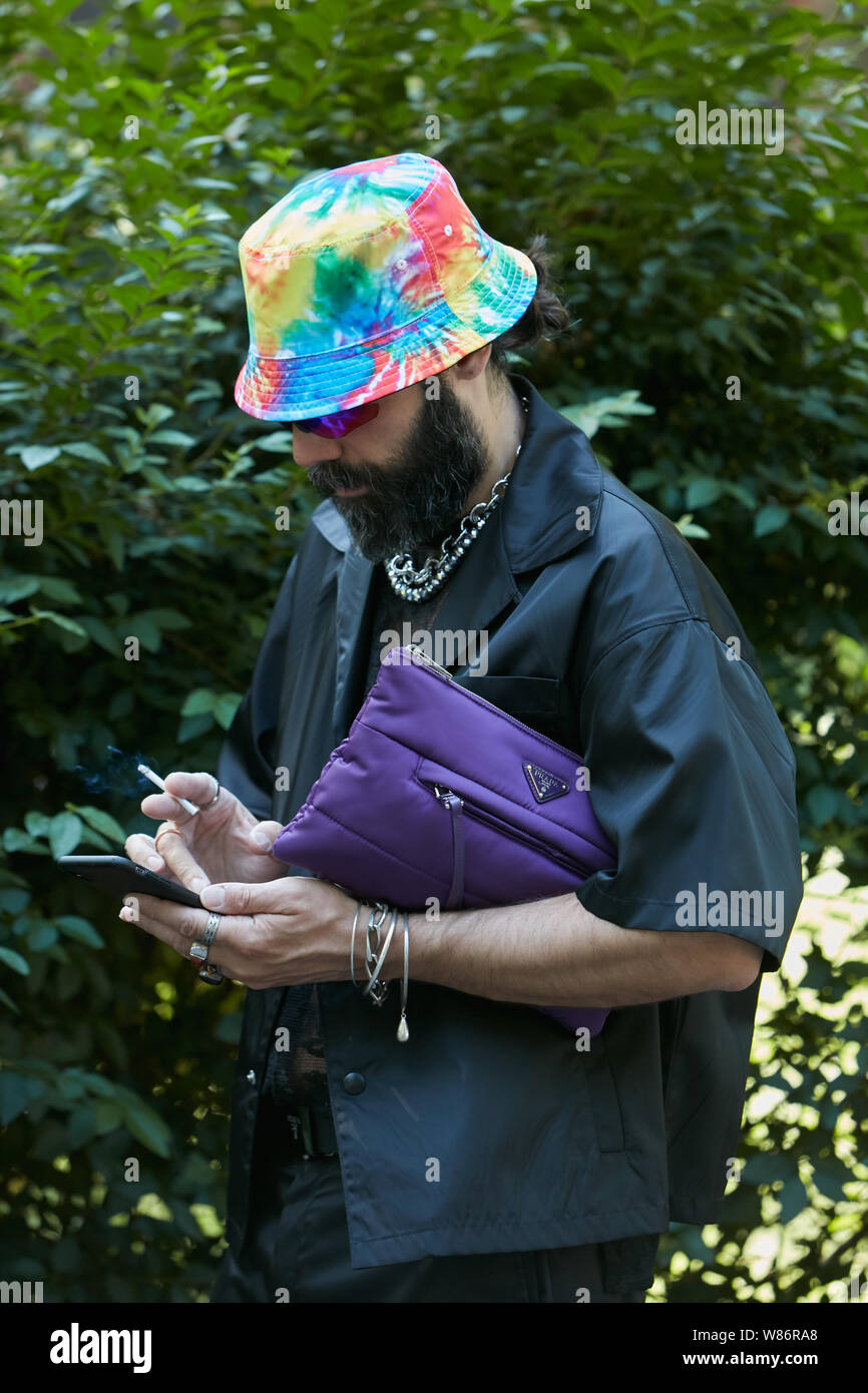 MILAN ITALY JUNE 17 2019 Man with purple Prada bag black jacket and colorful hat looking at smartphone before Fendi fashion show Milan Fashion Stock Photo Alamy