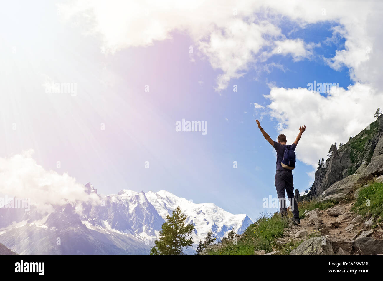 Young man in the mountains standing with his hands raised Stock Photo