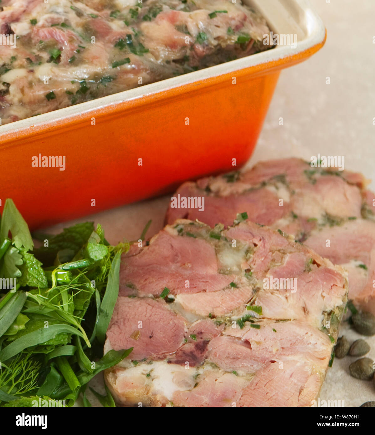 home made ham hock terrine in an orange terrine dish served with mayonnaise and herbs. Stock Photo