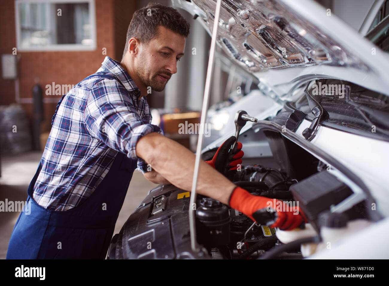 Man works at the car service under the fixation of a broken car engine. Stock Photo