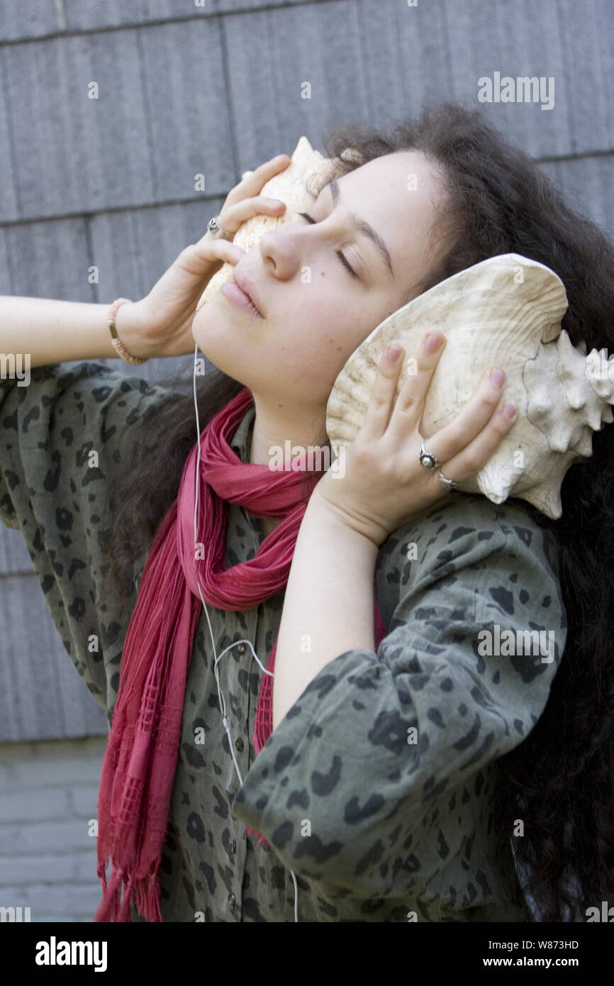 Listening to the natural sounds through a conch shell rather than an iphone. Stock Photo