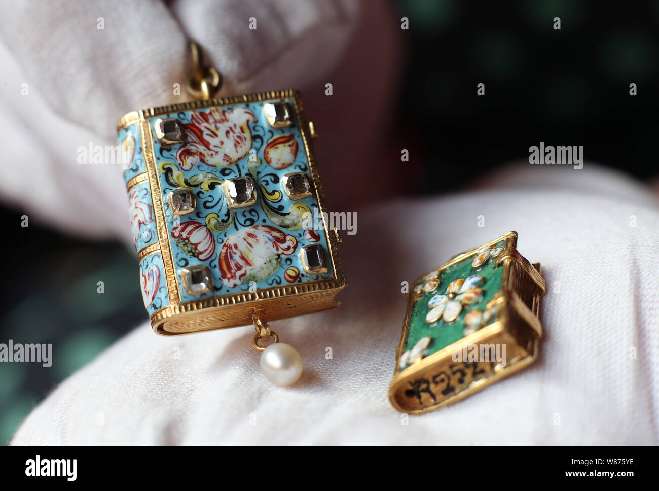 A couple of gold and enamel pendants (c.1640-1660) in the shape of books, with one (right) bearing a Nazi inventory number on the book edge, applied when they were confiscated from the French Rothschilds during the Second World War, at Waddesdon Manor, Buckinghamshire, ahead of the opening of A Rothschild Treasury exhibition, which will be held in a new, permanent, gallery containing more than 300 rarely seen objects spanning two millennia - from a 1st-century cameo of Augustus Caesar's grandson, via jewellery given as presents from Queen Victoria, to objects bearing Nazi inventory numbers. Stock Photo