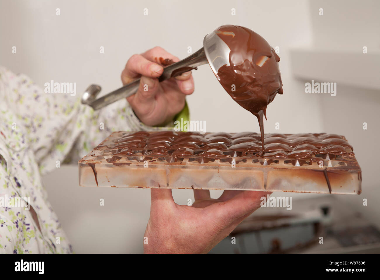 pouring molten chocolate into a mould to make chocolates. Stock Photo