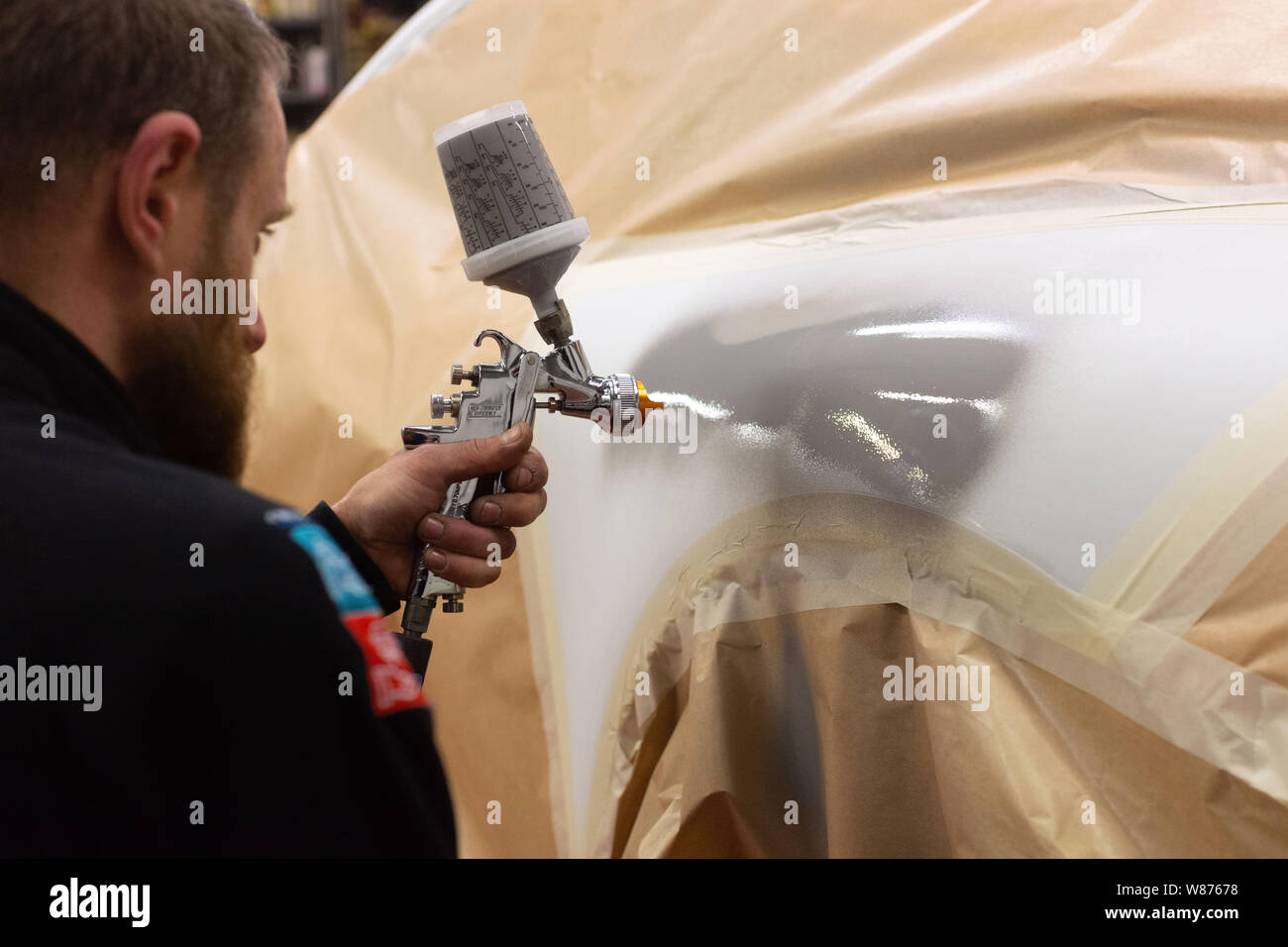“Bonhomme Automobile” car body shop in Montelier (southeastern France). Worker spraying paint on a car body. Stock Photo