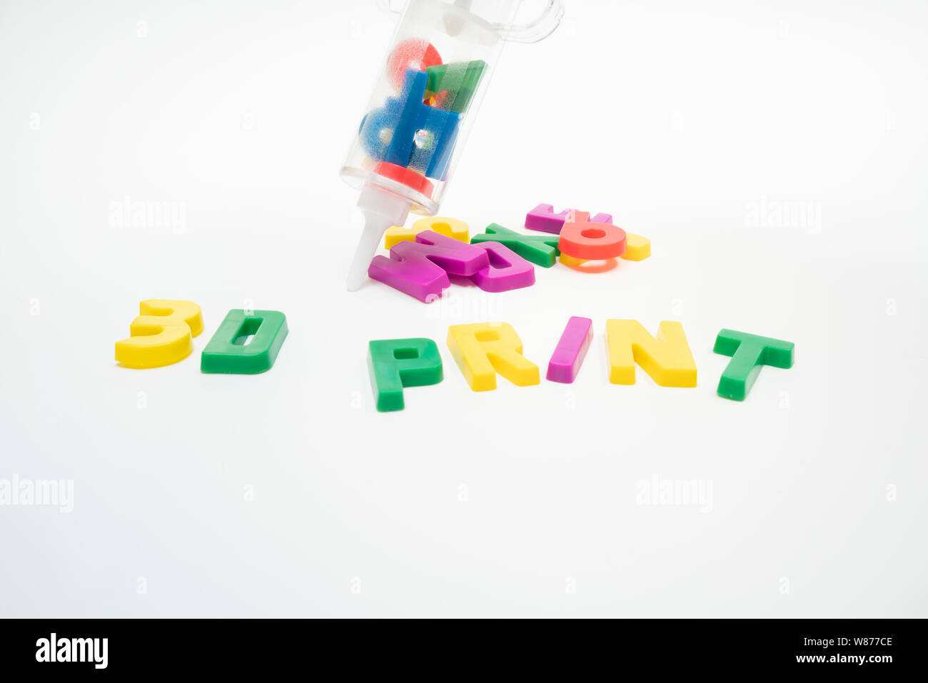 a plastic syringe full of plastic letters and numbers next to some others spelling out 3D PRINT Stock Photo