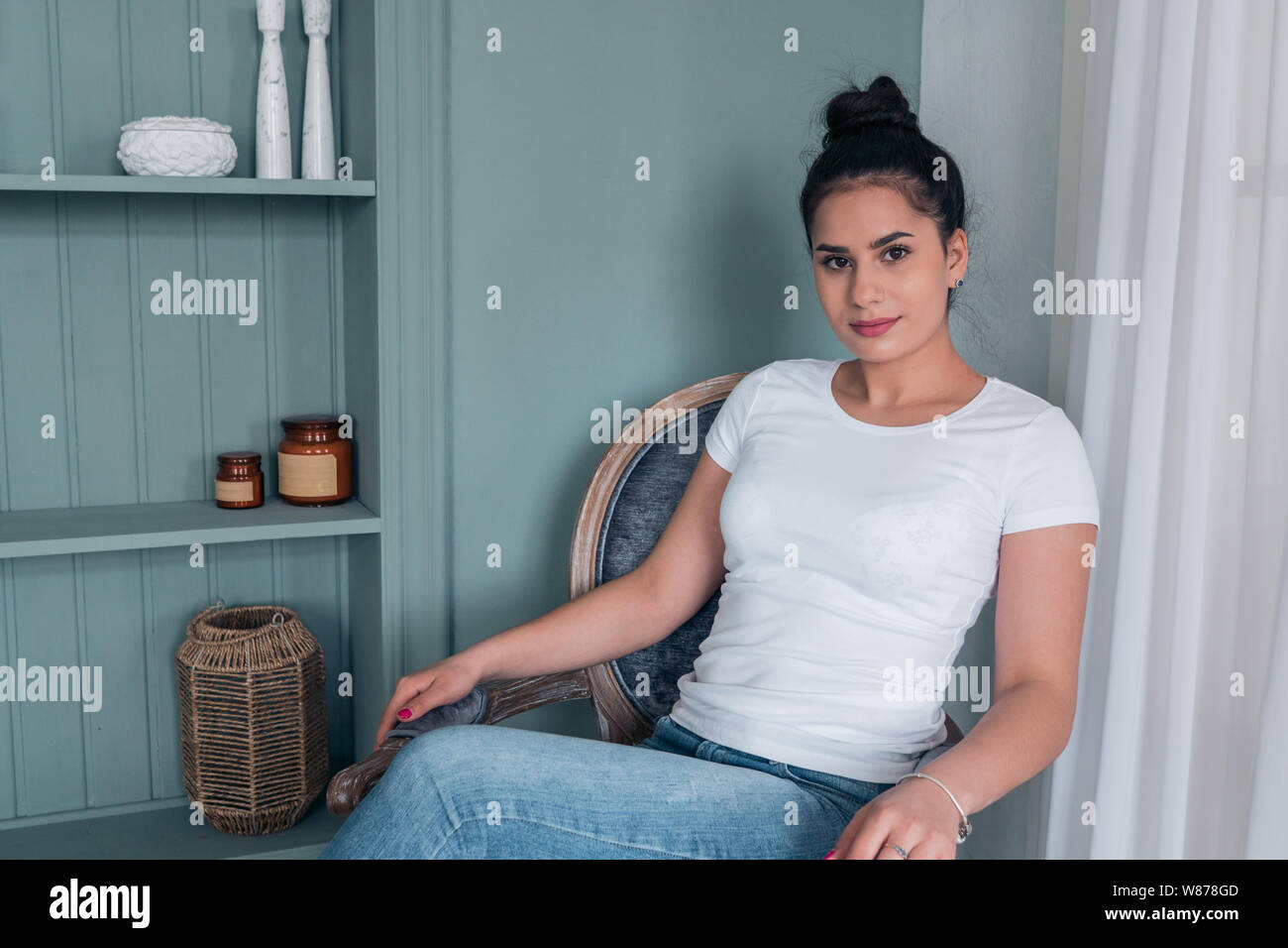 A girl in a white t-shirt sitting in a chair. Women's casual wear Stock Photo