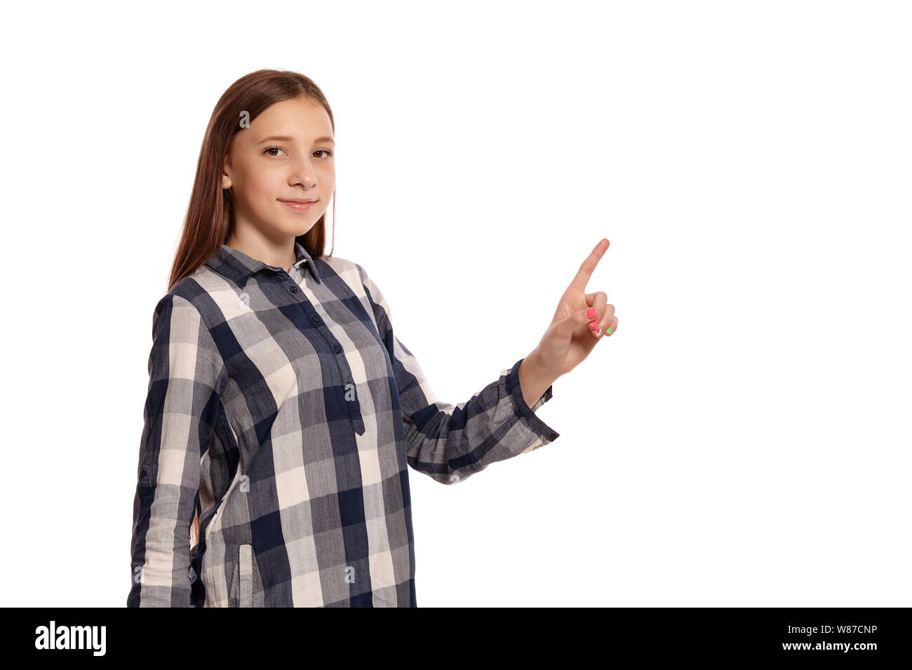 Beautiful teenage girl in a casual checkered shirt is posing isolated on white studio background. Stock Photo