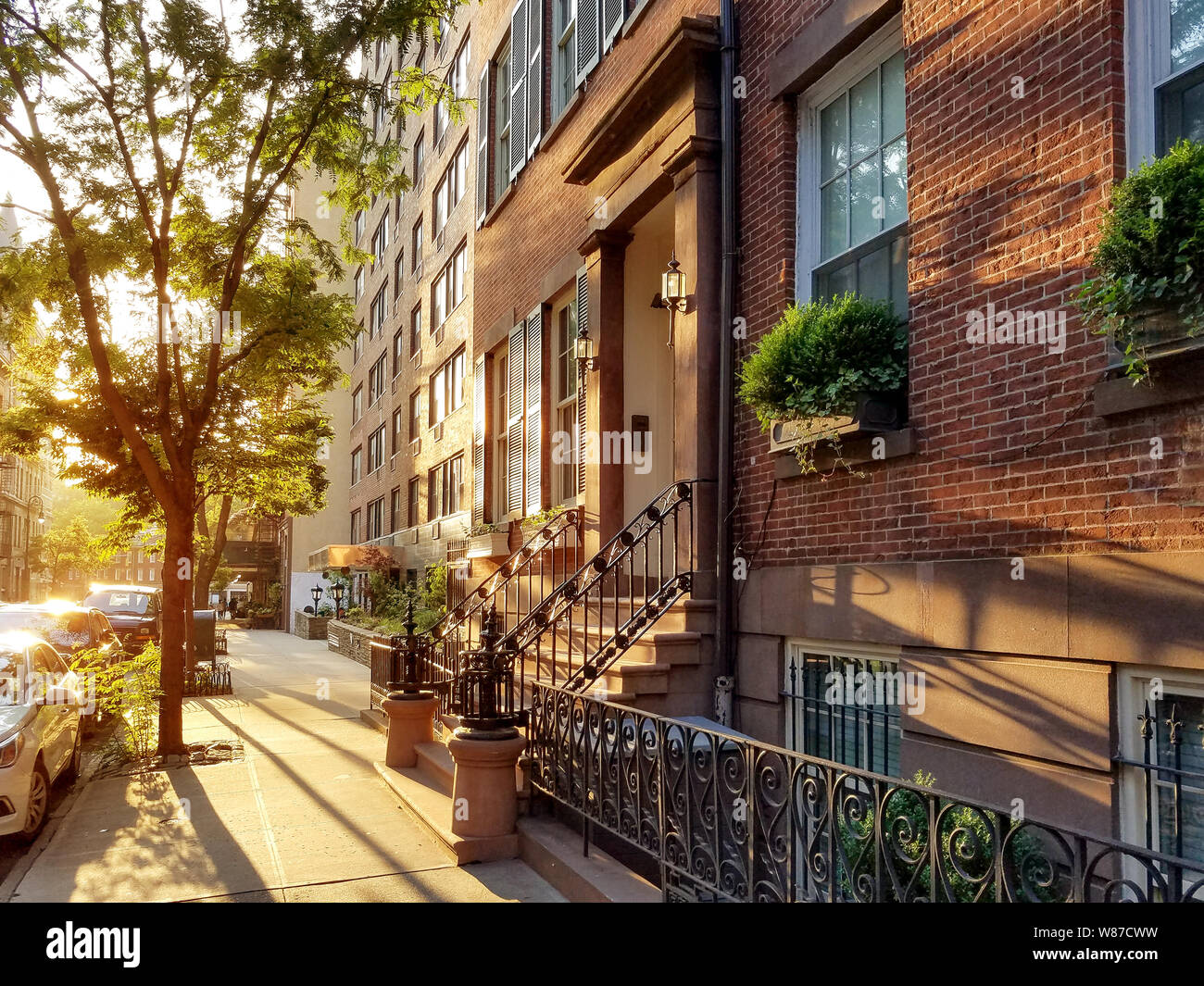 Old brownstone buildings along a quiet neighborhood street in Greenwich Village, New York City NYC Stock Photo