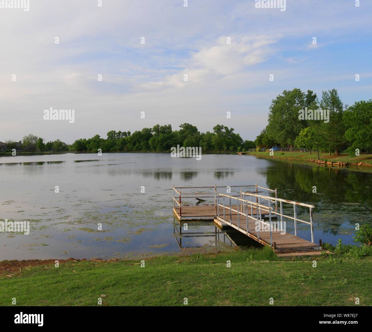 View of a lake with a floating wooden dock with railings Stock Photo ...