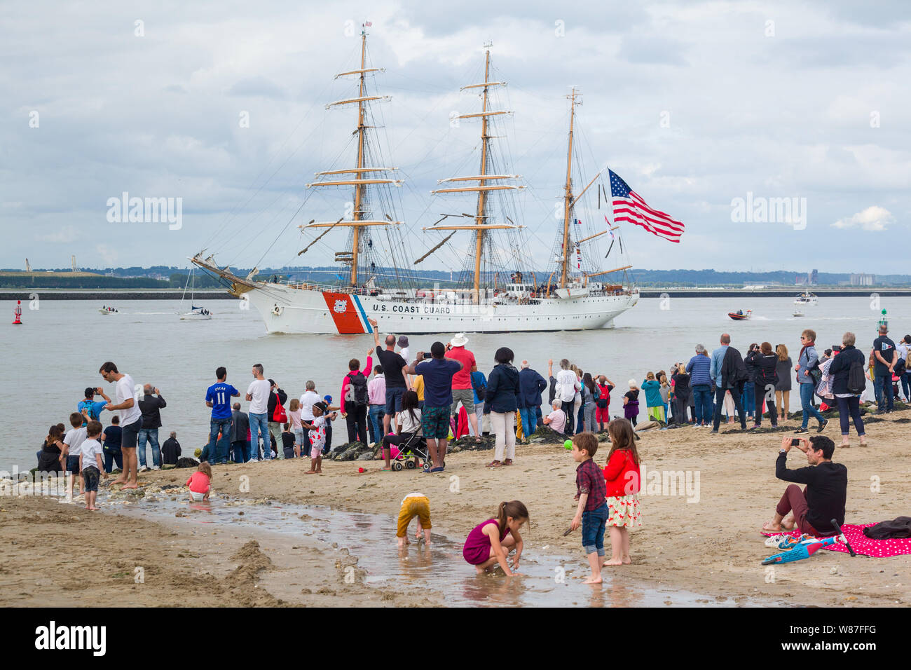 Spectators watch the tall ship US Coastguard USCGC Eagle (WIX-327), returning from the Rouen Armada from the beach at Honfleur, Normandy, France Stock Photo