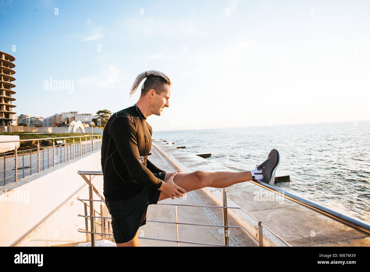 man stretching on the street. Runner on the city. Stock Photo