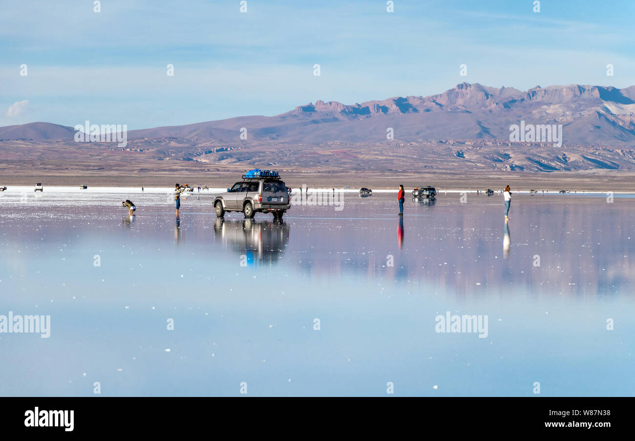 Water mirror in Salar de Uyuni, Uyuni, Bolivia : Tourists reflects in white salt flats lake and enjoy Jeep tour activities in Bolivian Salt Desert Stock Photo